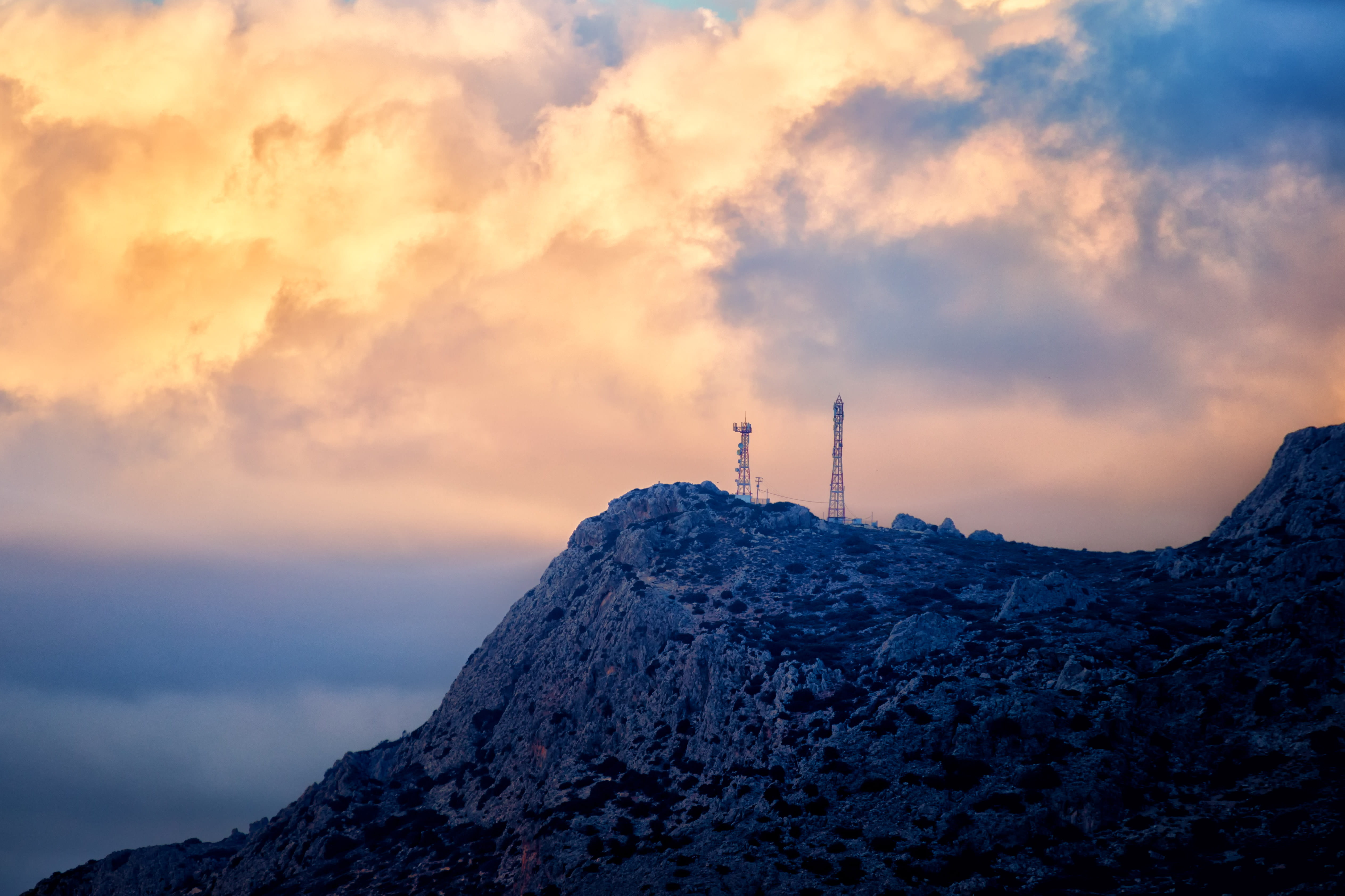 two communication towers on mountain top during sunset, cloudscape