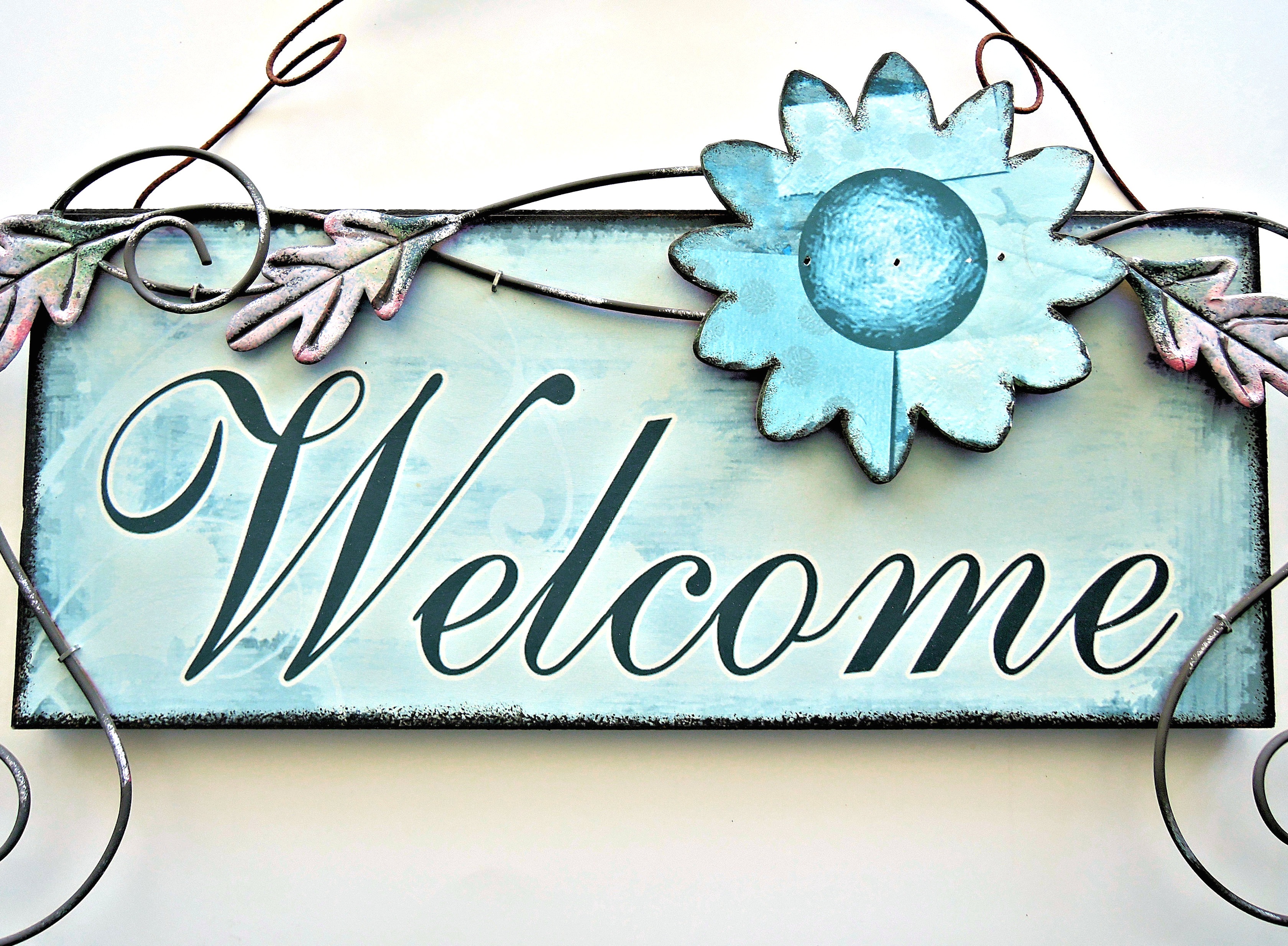 blue and black welcome signage hanging on wall, painted door sign