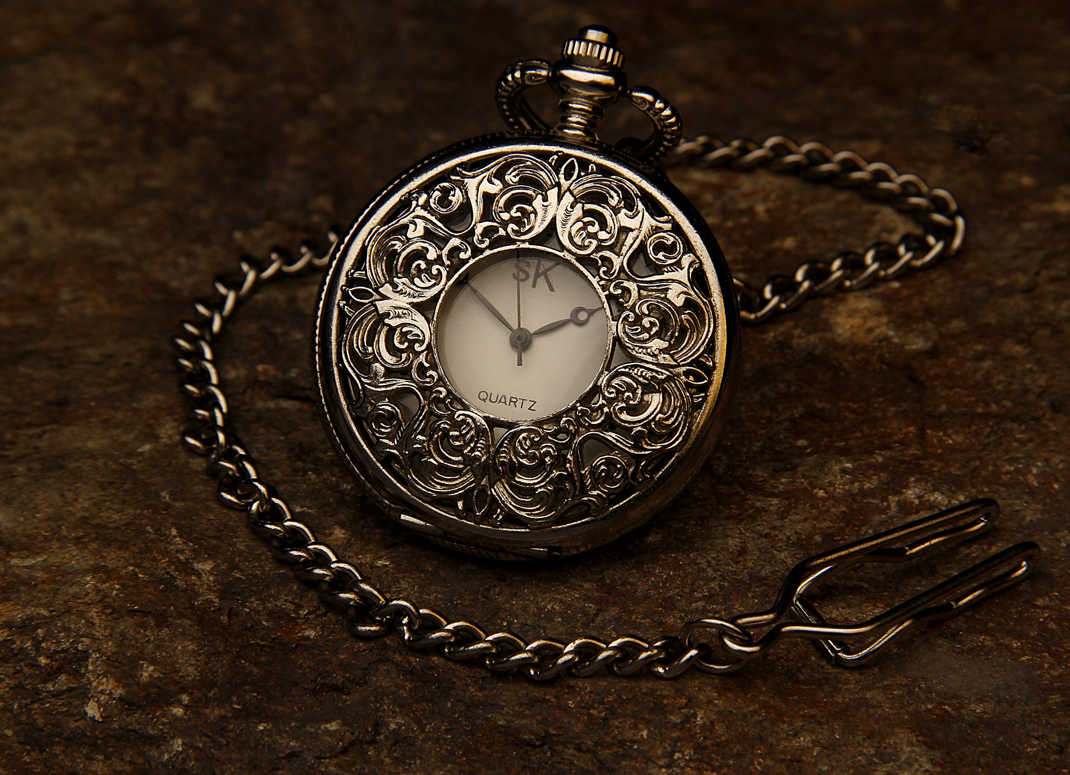 silver-colored pocket watch with link strap, jewel, chain, stone