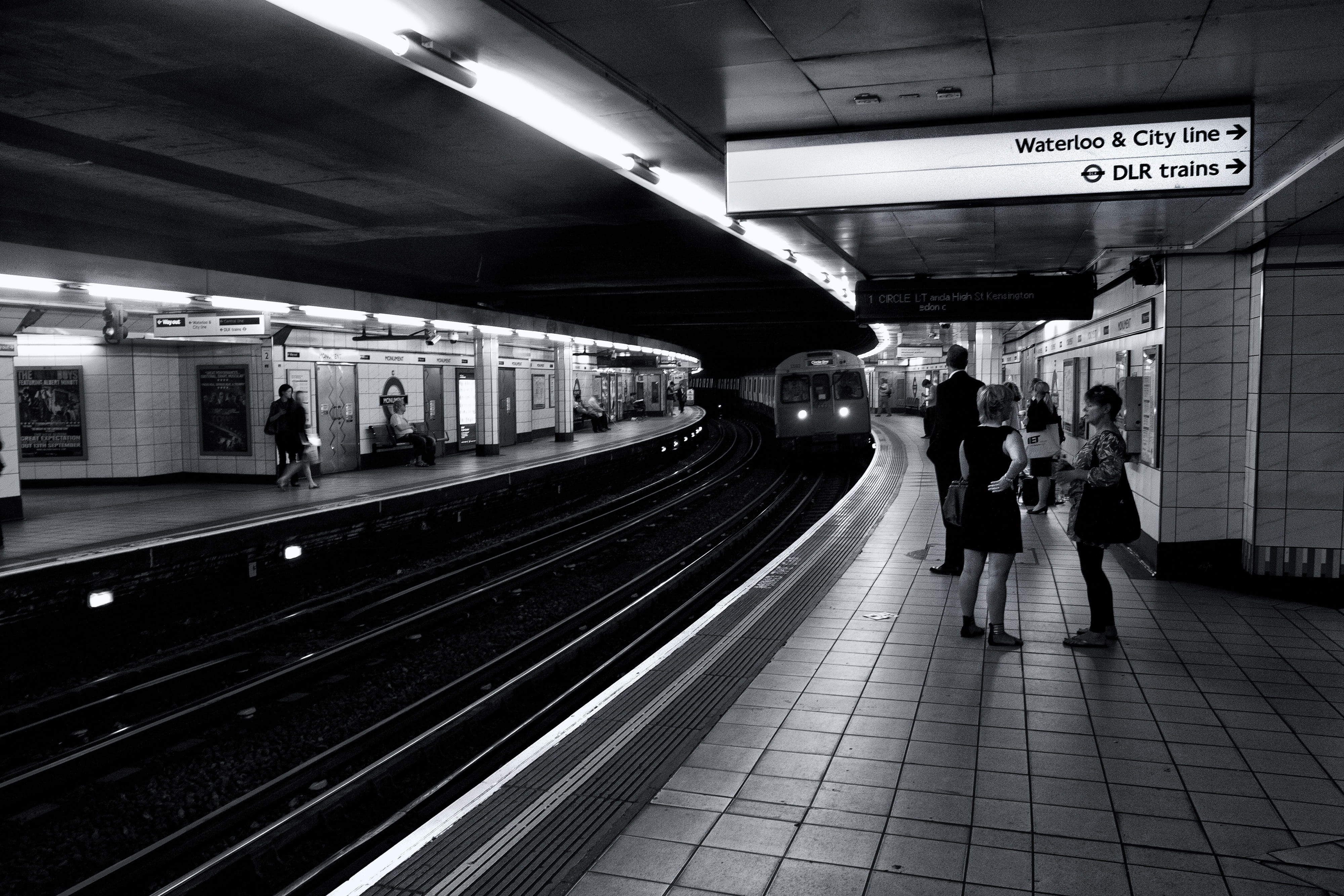 Monochrome shot of subway passengers as they wait for their train on the London Underground