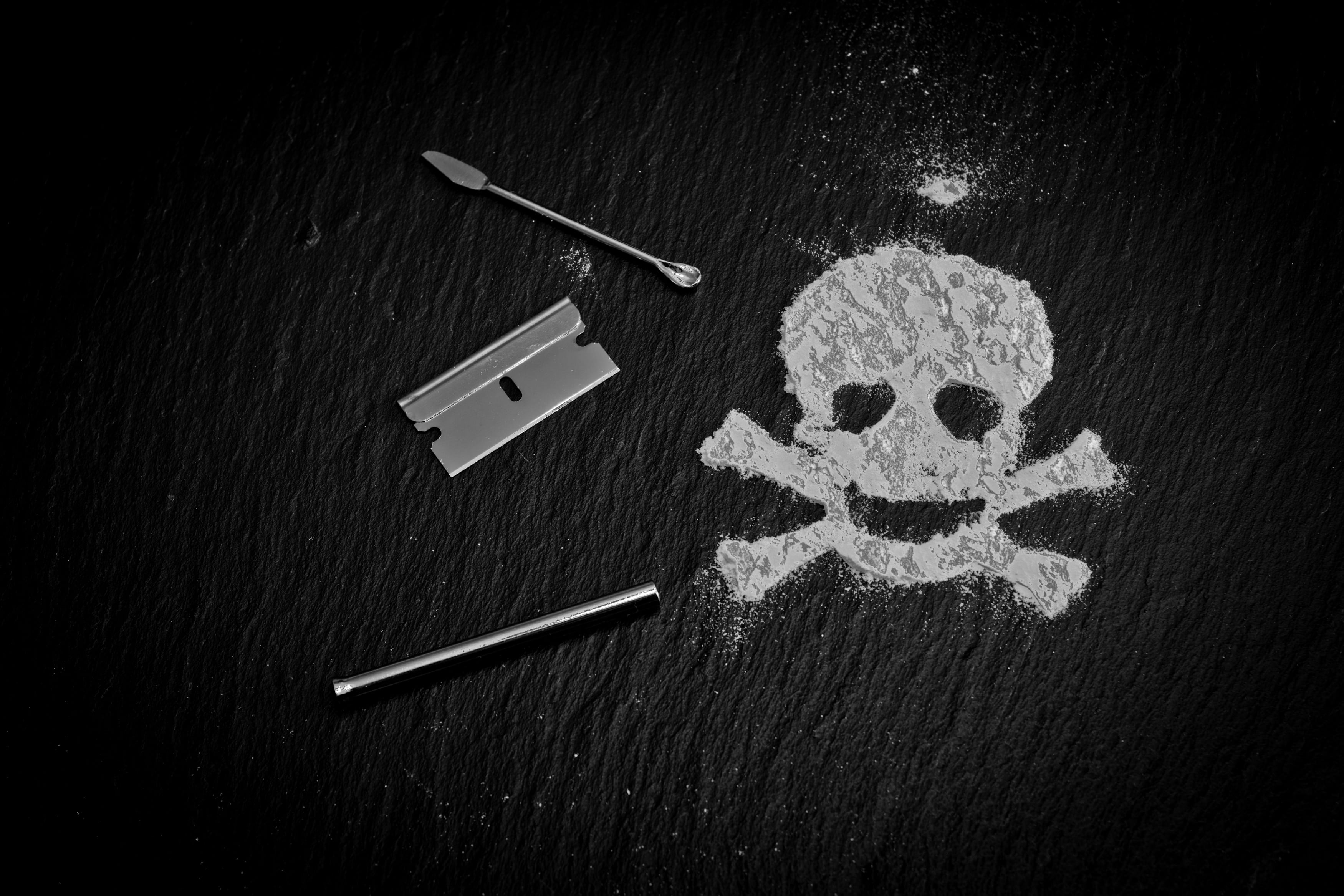 grayscale photography of door latched beside skull powder, drugs