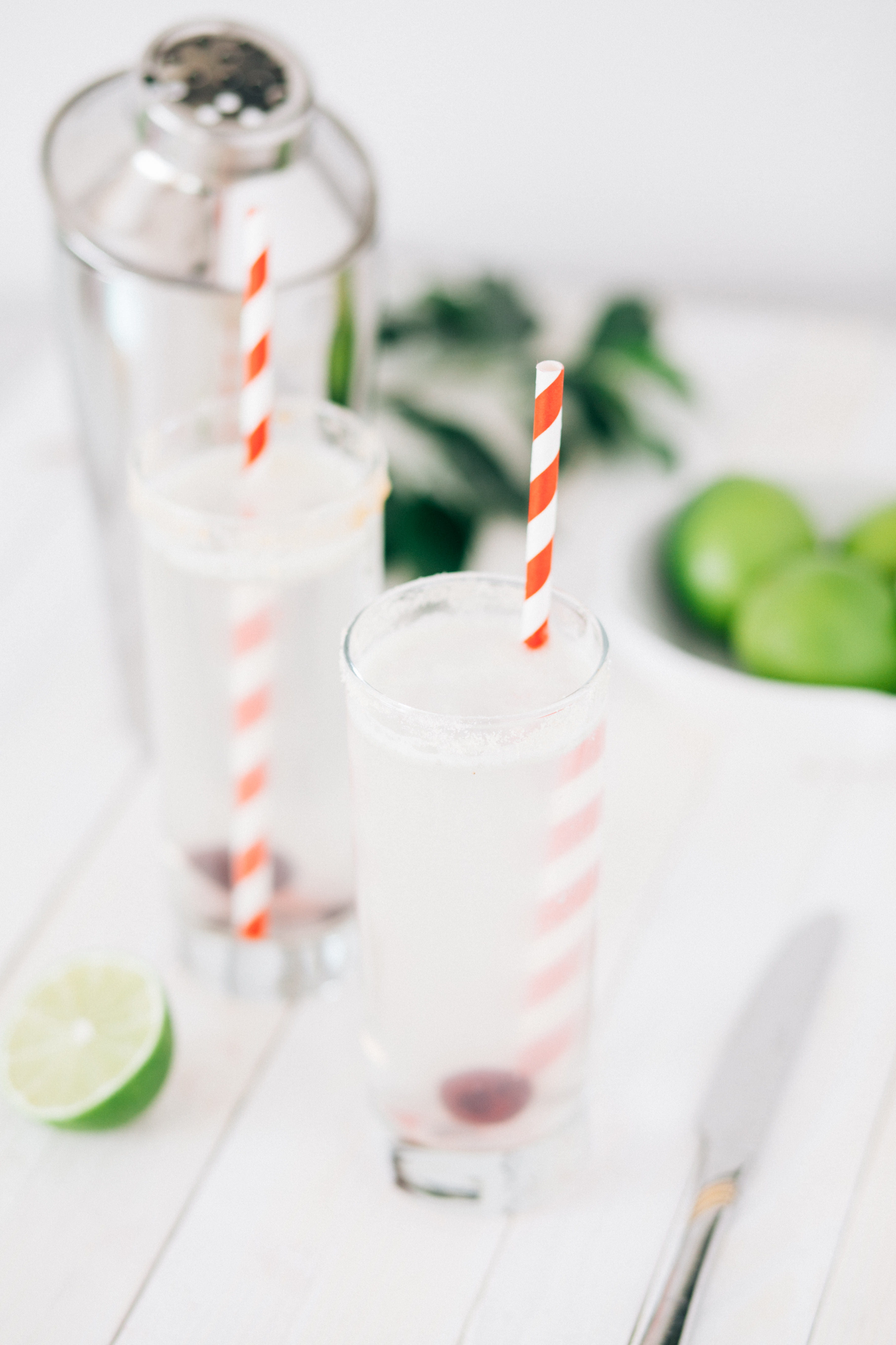 two round clear glass drinking cups near gray stainless steel knife, selective focus photography of drink with straw