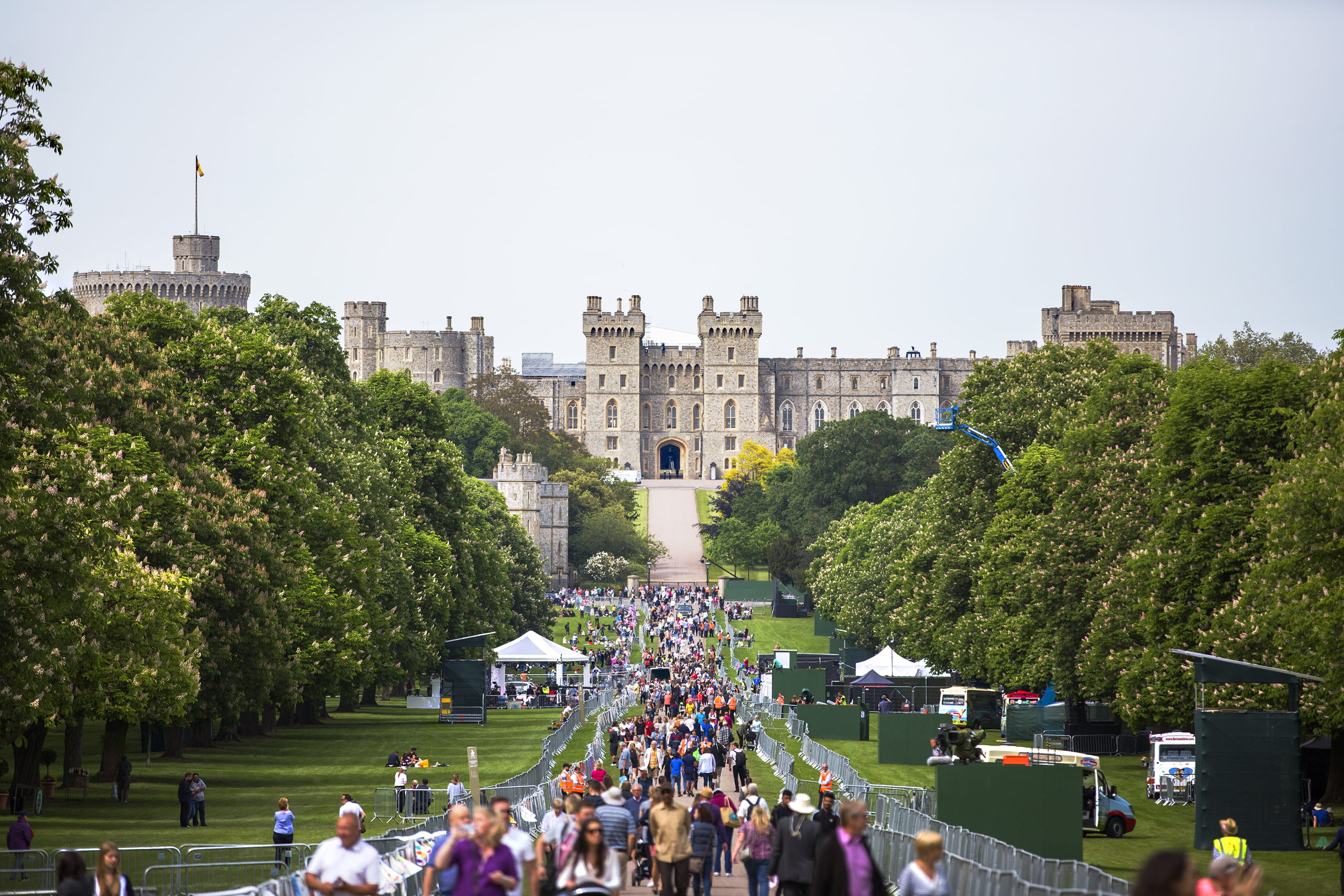 people at the park and castle at the distance during day, photo of people walking along pathway near castle