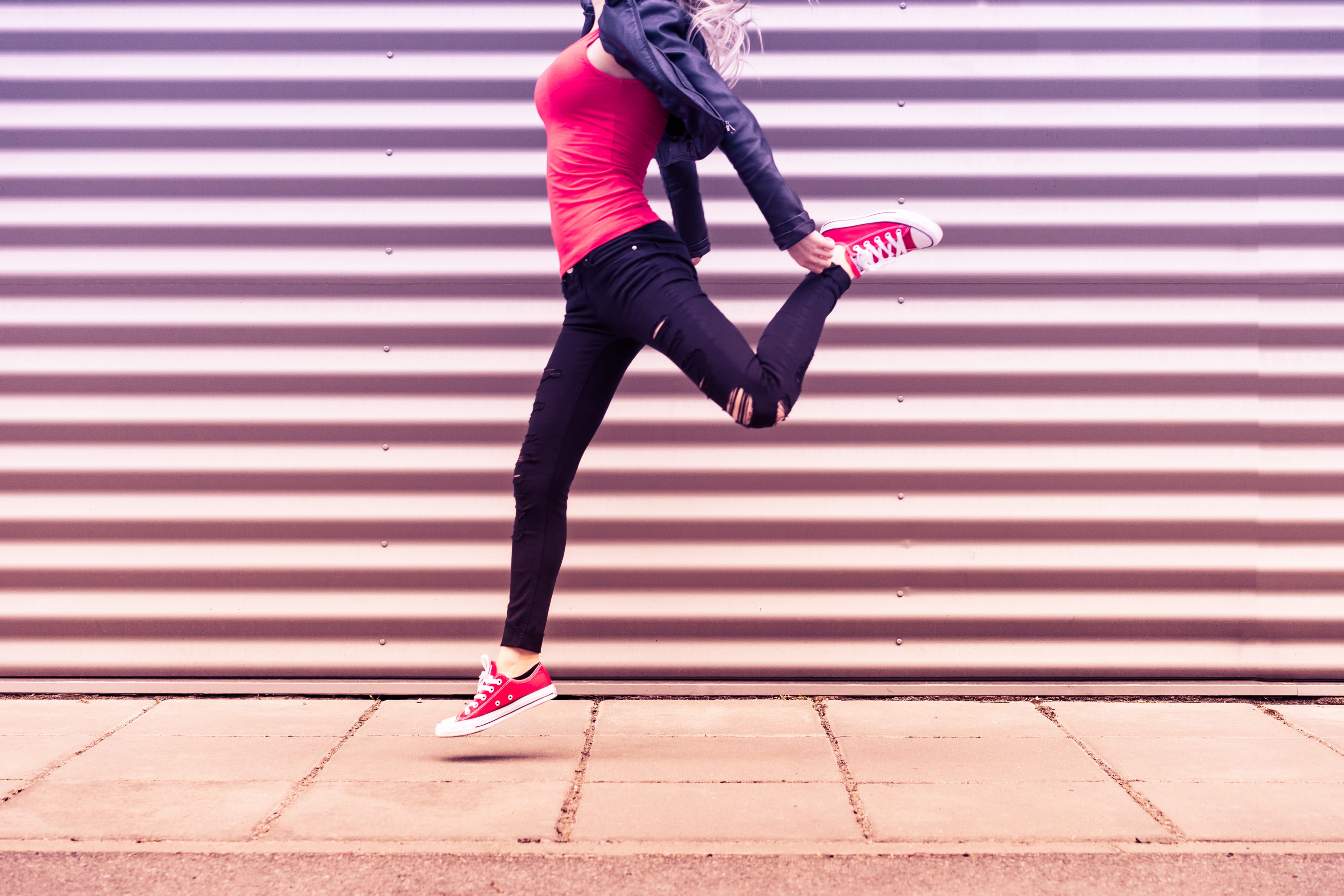 Young Happy Woman Jumping in Front of Metal Wall, colorful, emotions