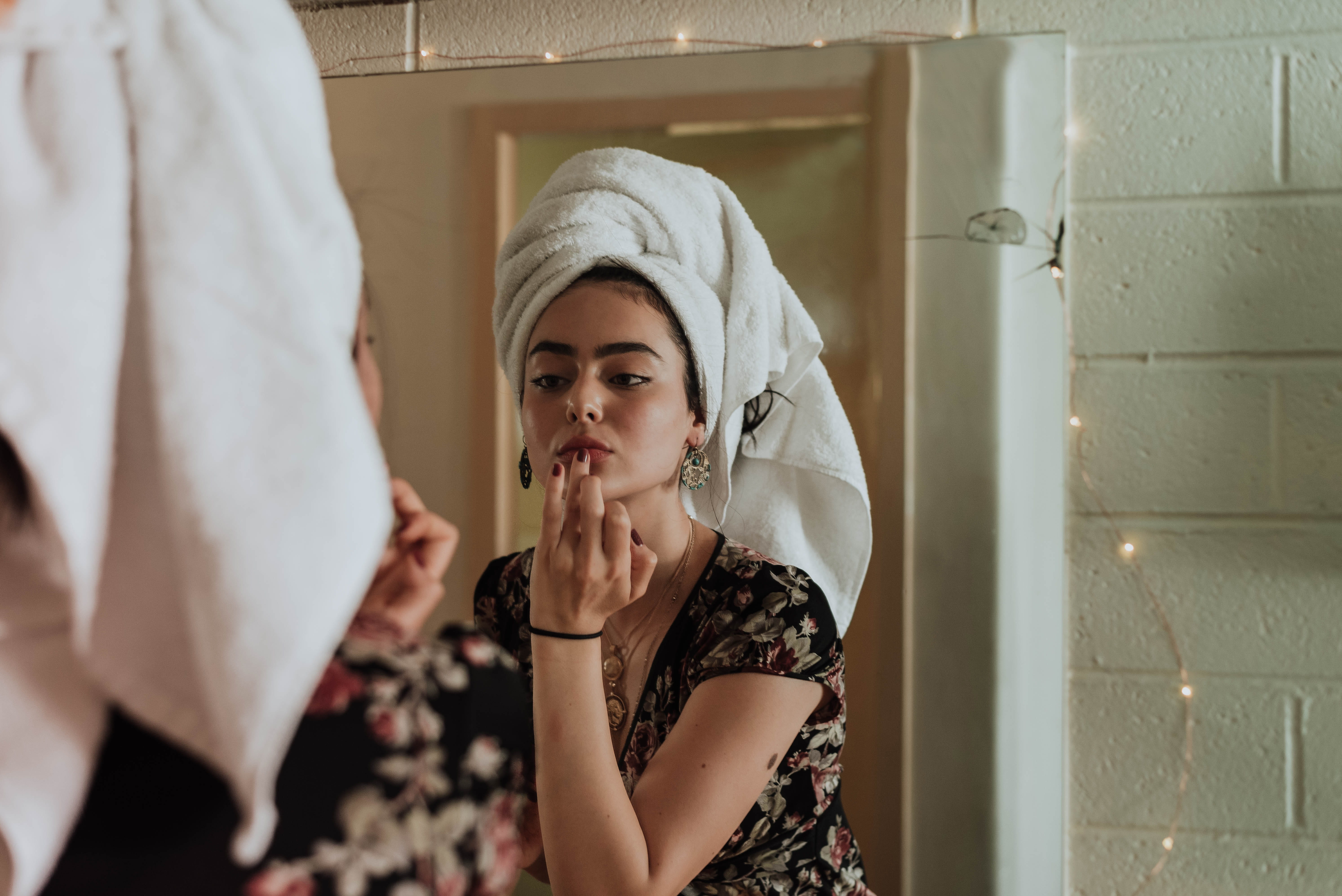 woman putting makeup in front of mirror, woman in front of mirror putting lipstick