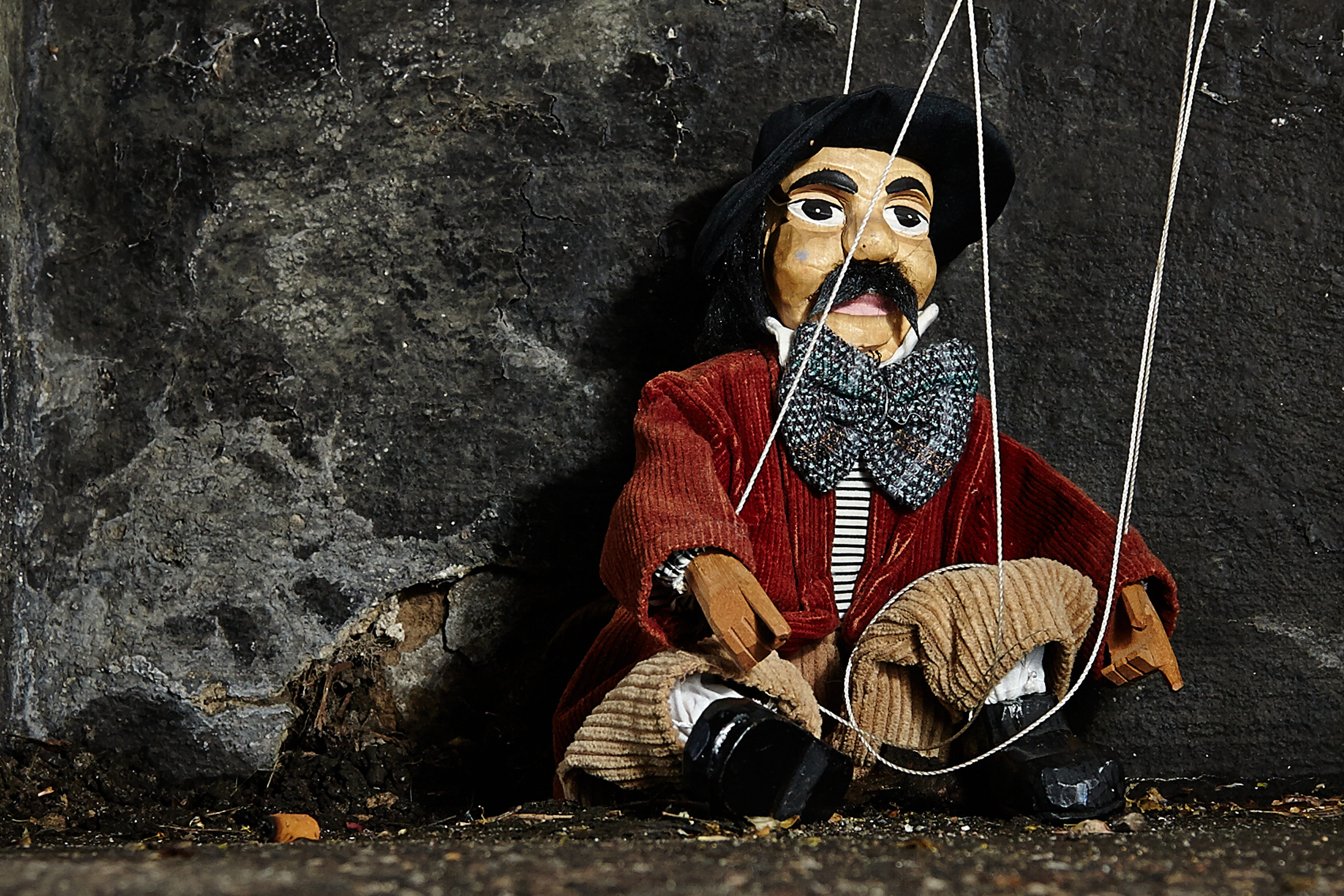 male string puppet leaning on black wall, Marionette, Strings