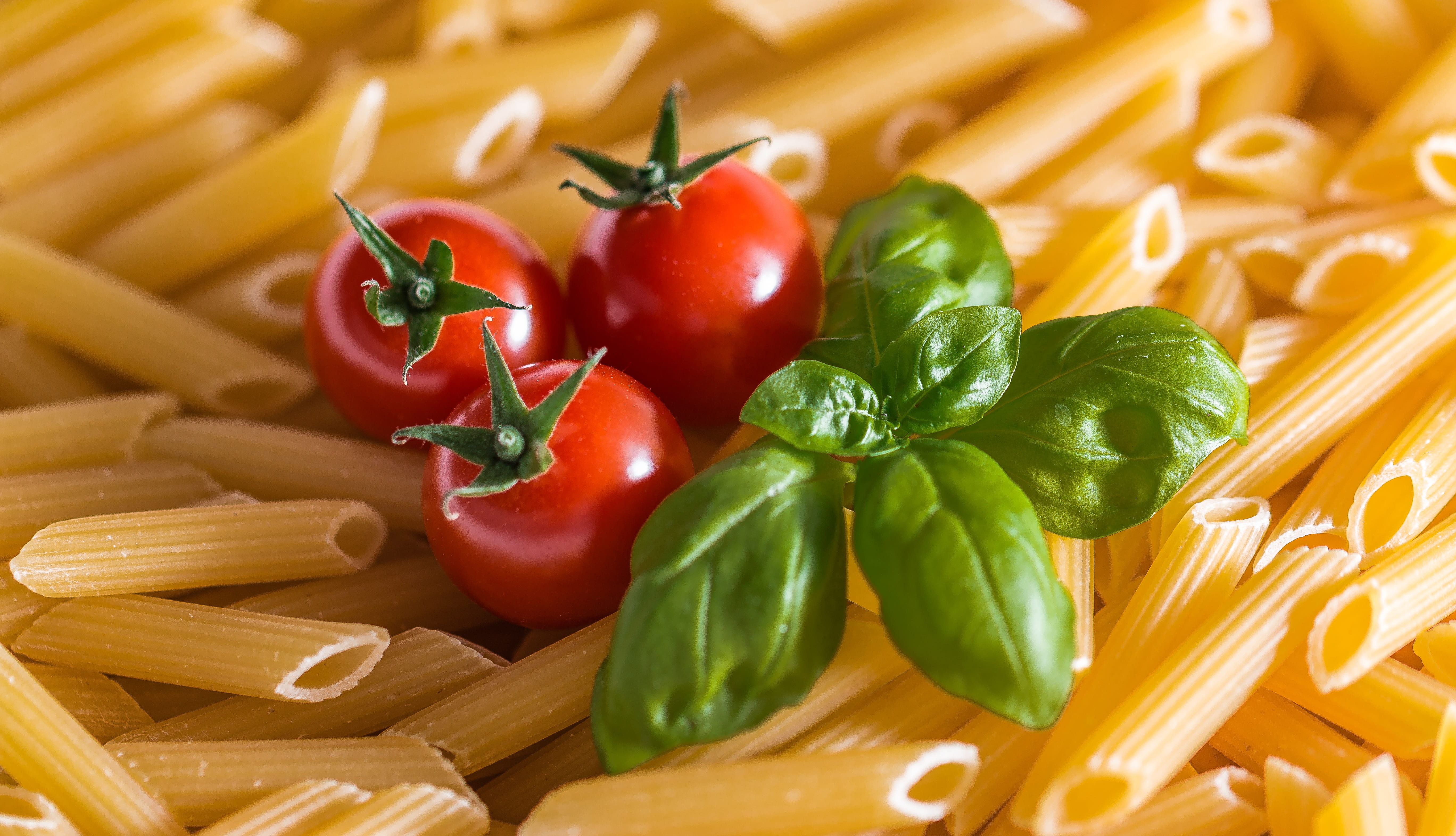 three red tomatoes on raw pasta, noodles, penne, dine, eat, food