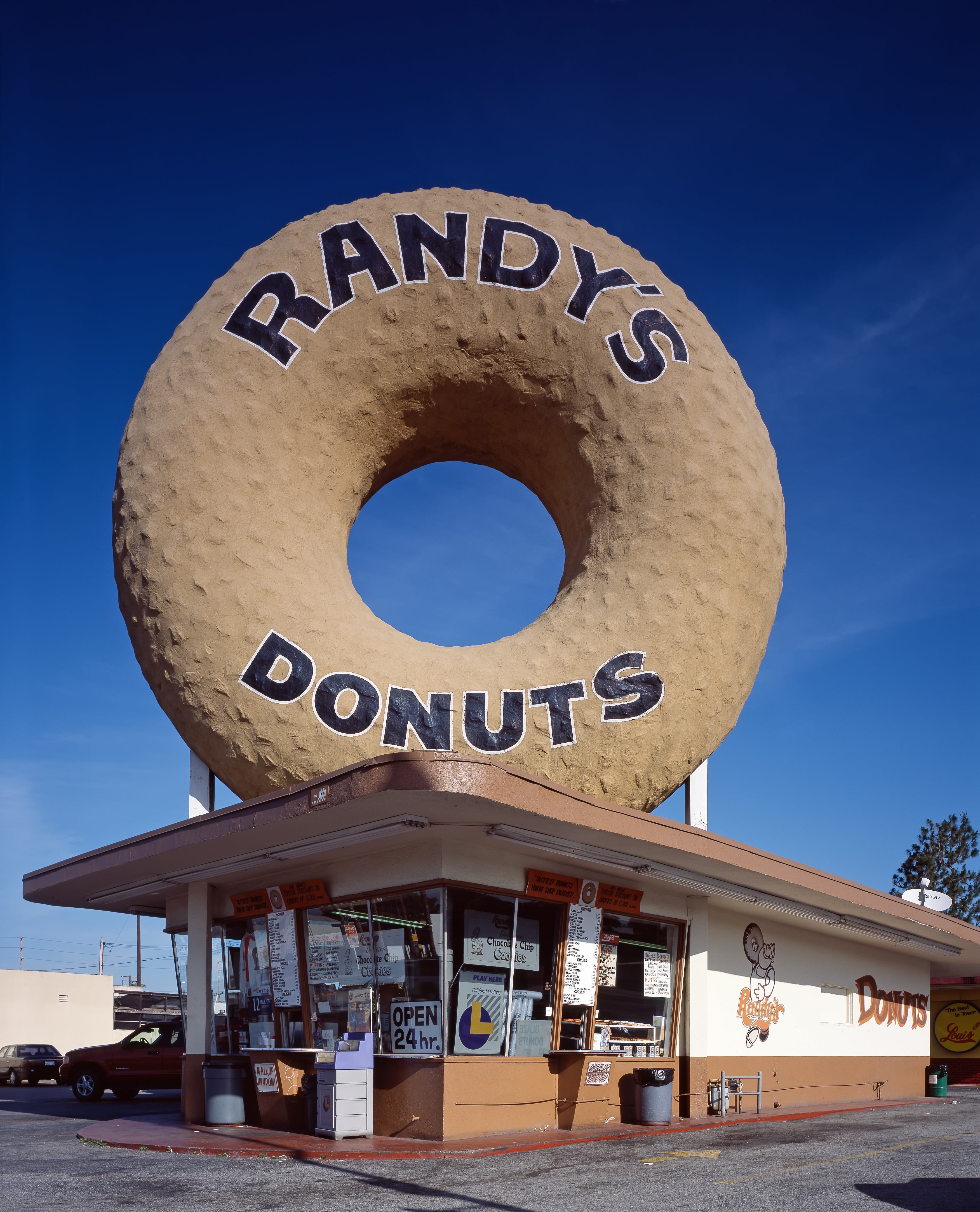 person taking photo of Randy's Donuts store at daytime, doughnut