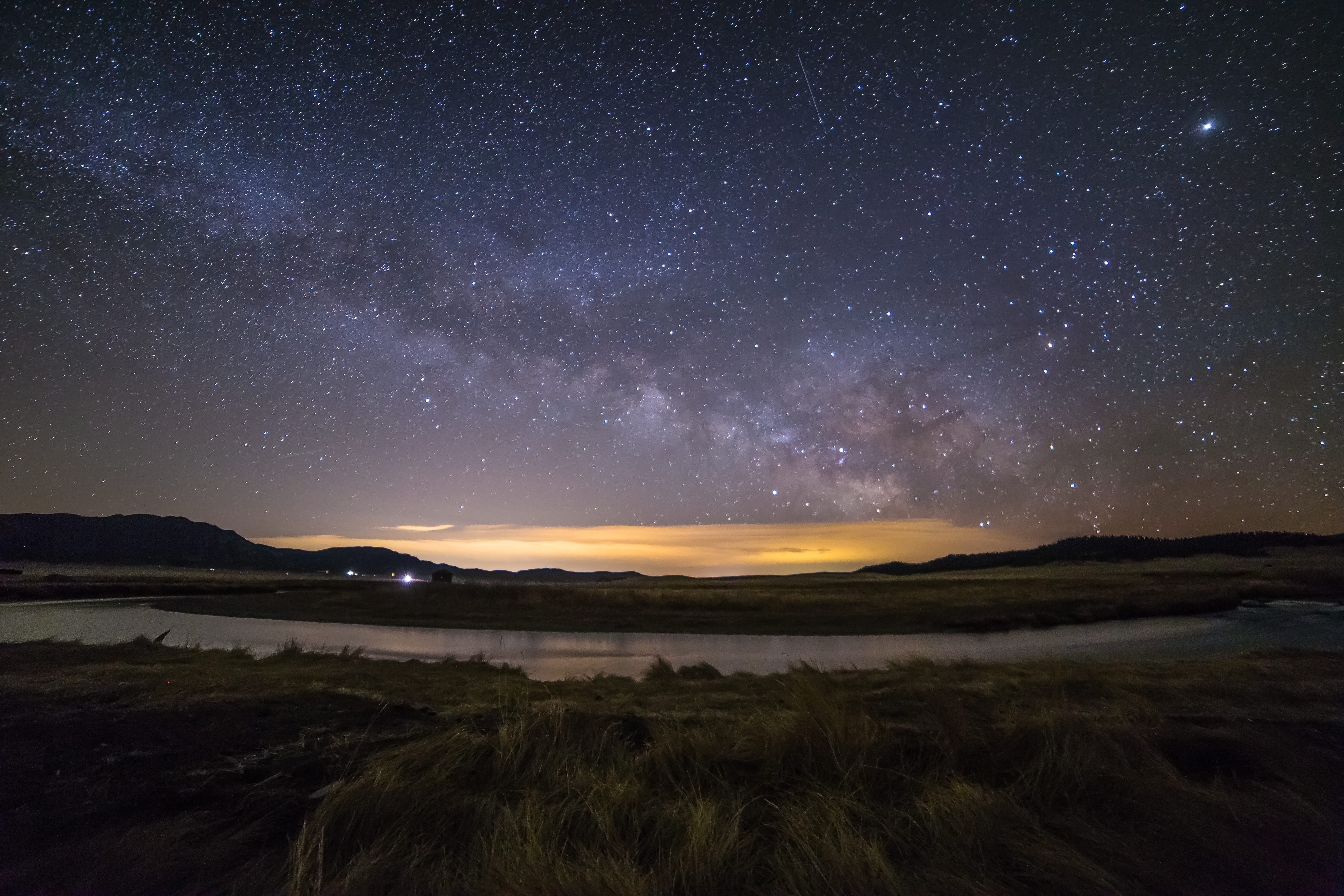 body of water under night sky, lake surrounded by green grass field under starry night