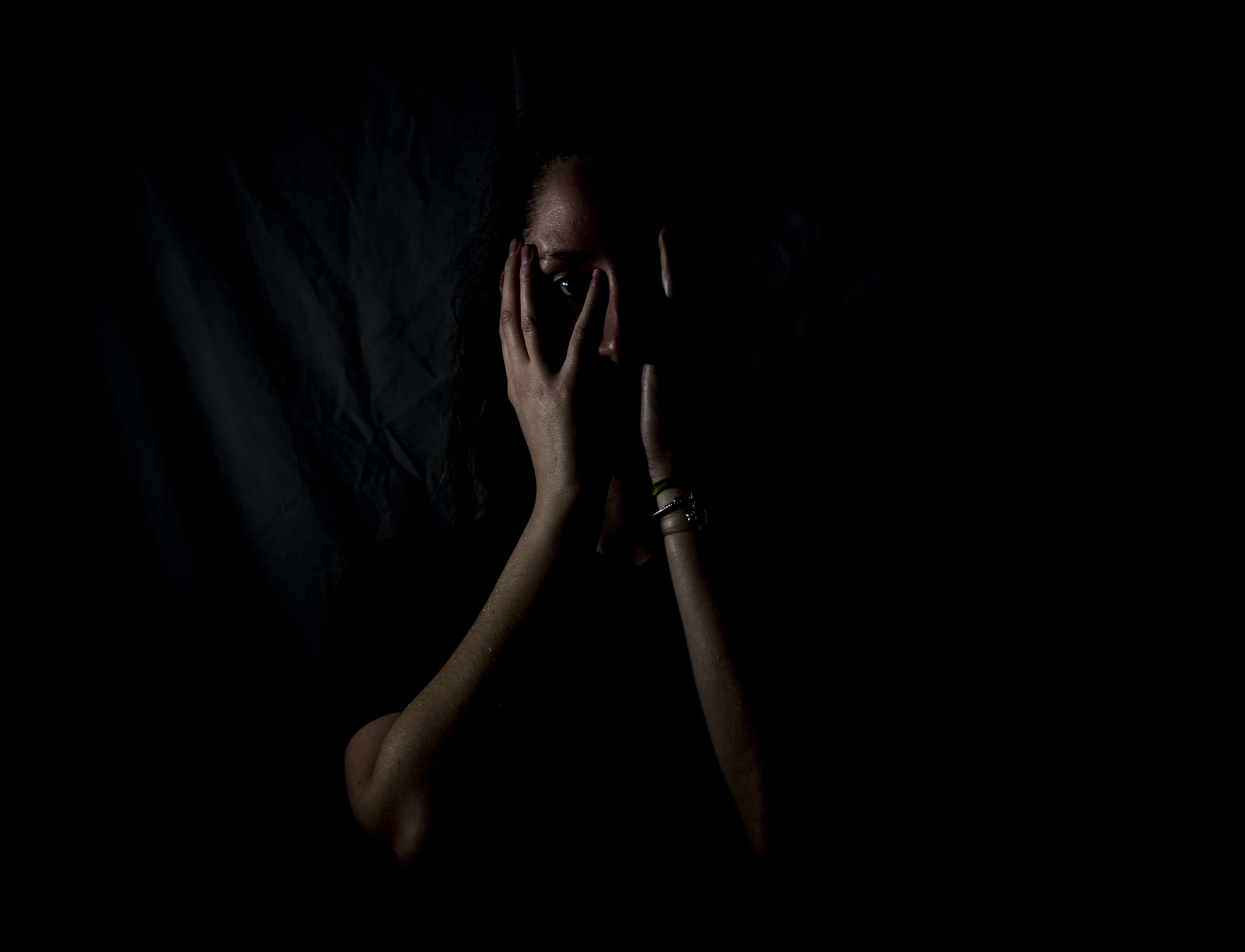 woman holding her face in dark room, untitled, F E A R, E S, S S