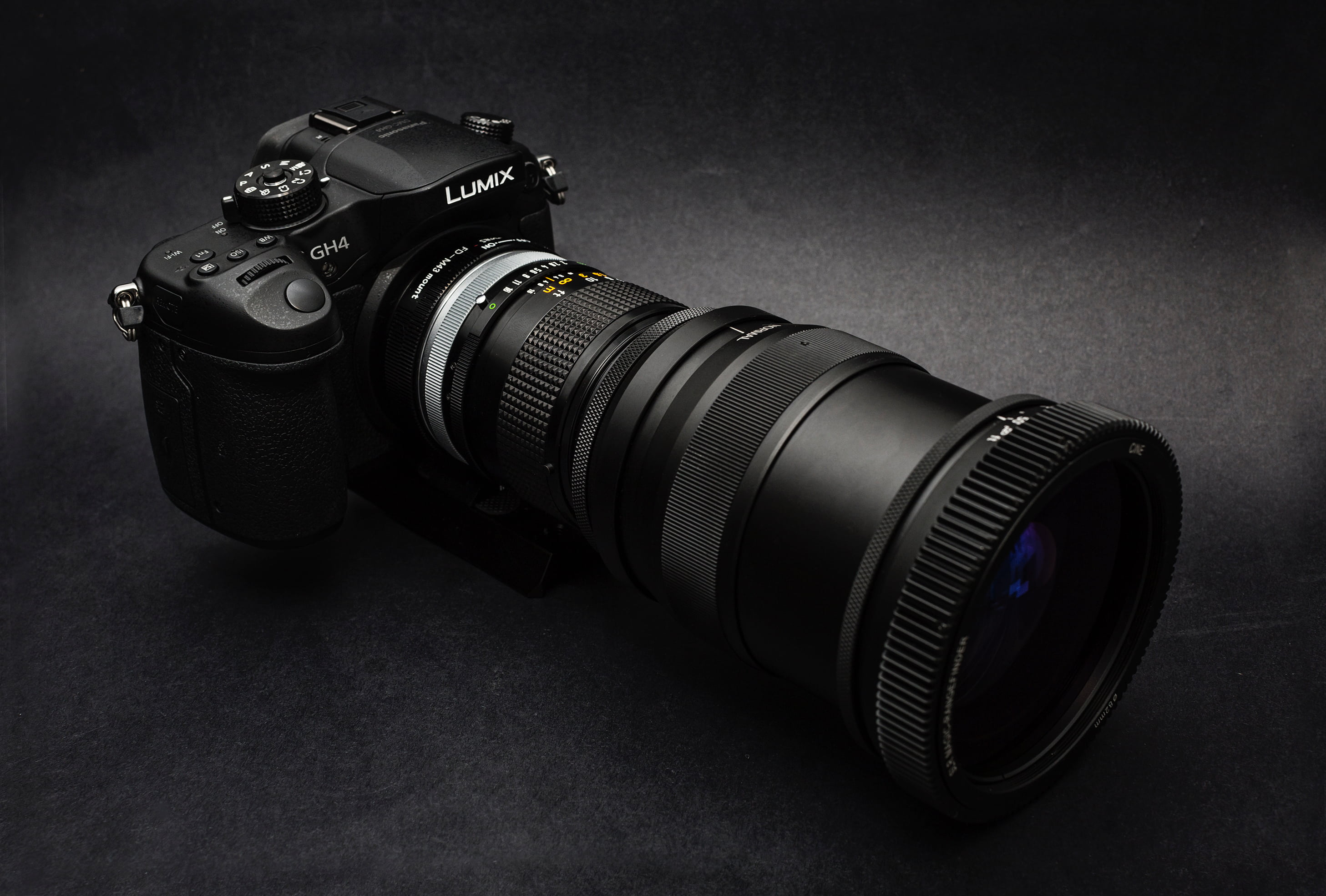 black Lumix DSLR camera on black surface, lens, manual, shutter