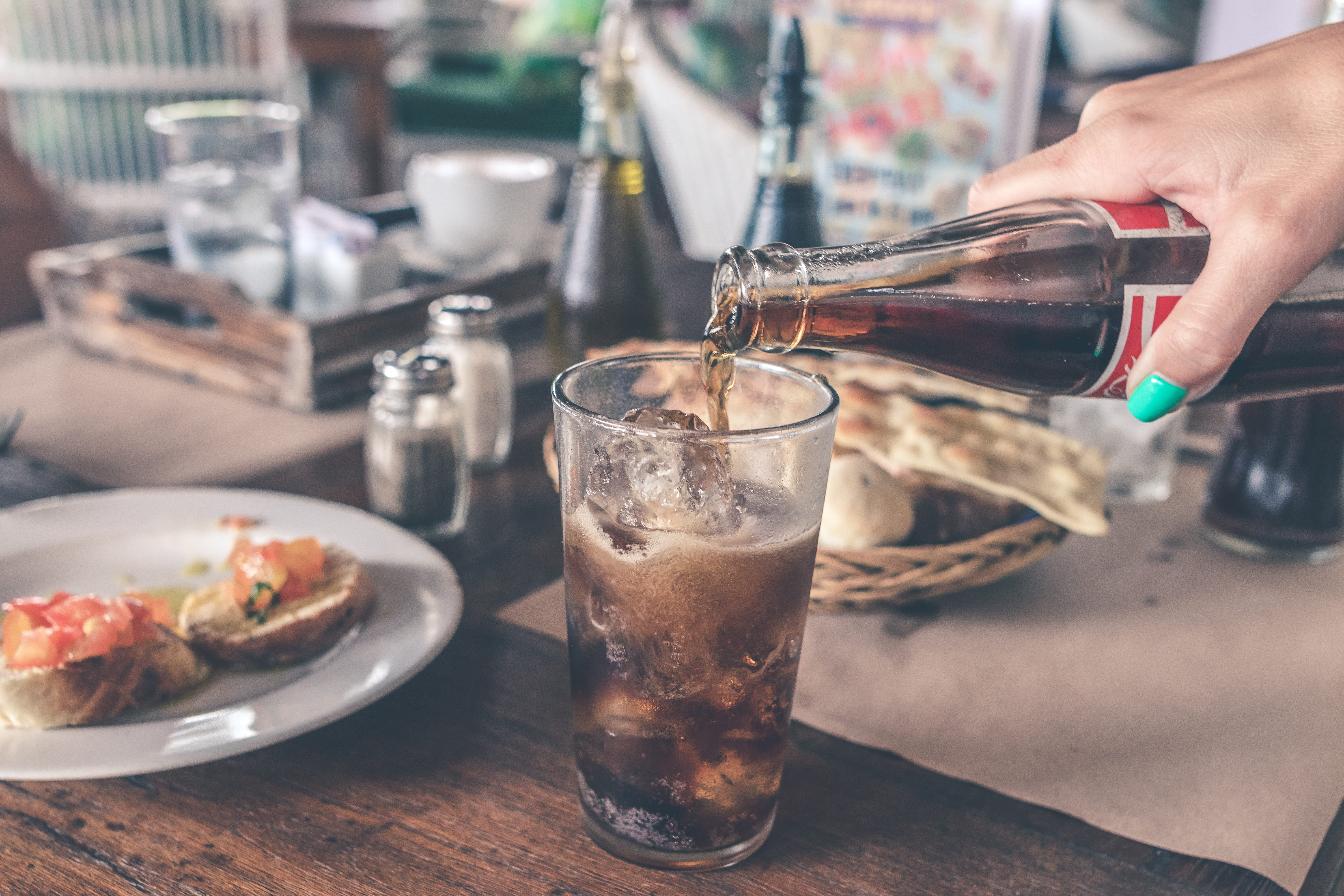 Pouring Cola with ice cubes, person pouring cola on highball glass
