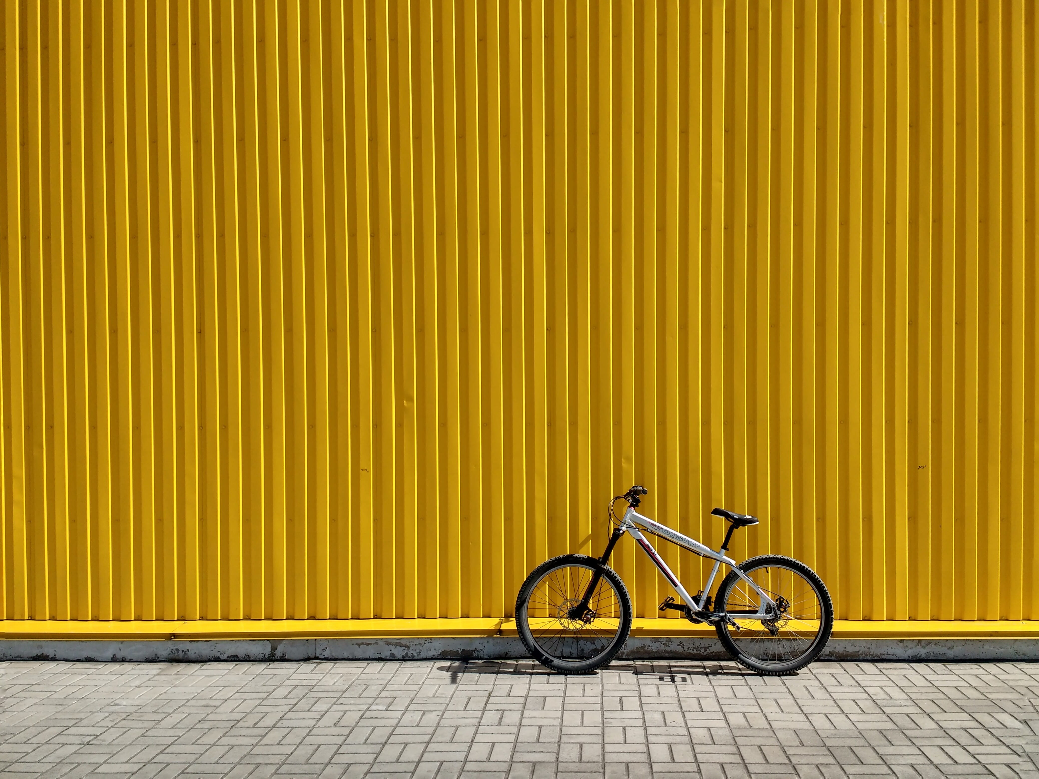 gray and black bike leaning on wall, bicycle leaning on yellow intermodal container