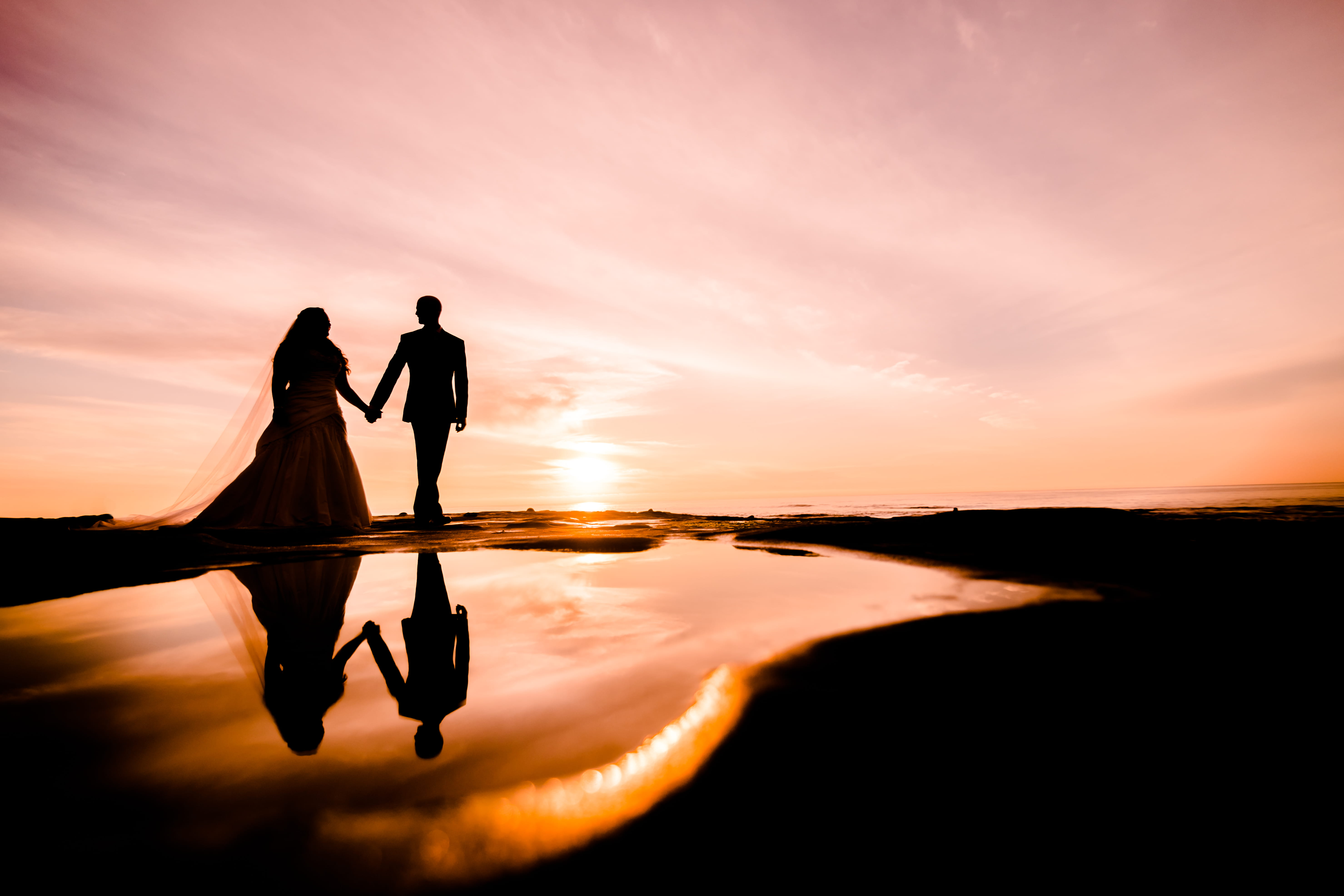 silhouette photography of couple walking near body of water, wedding