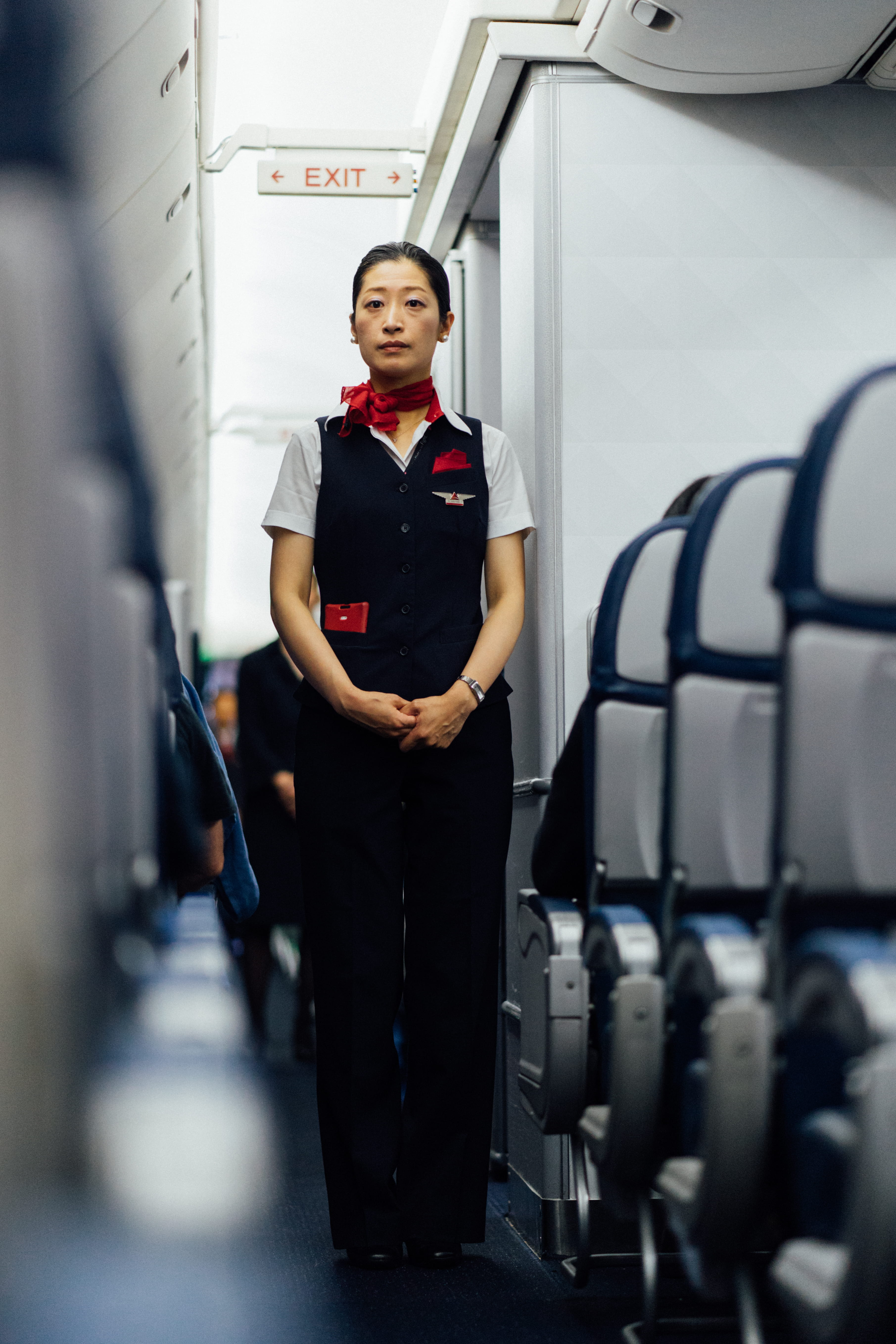 stewardess standing near exit inside plane, woman in black top and pants standing near exit