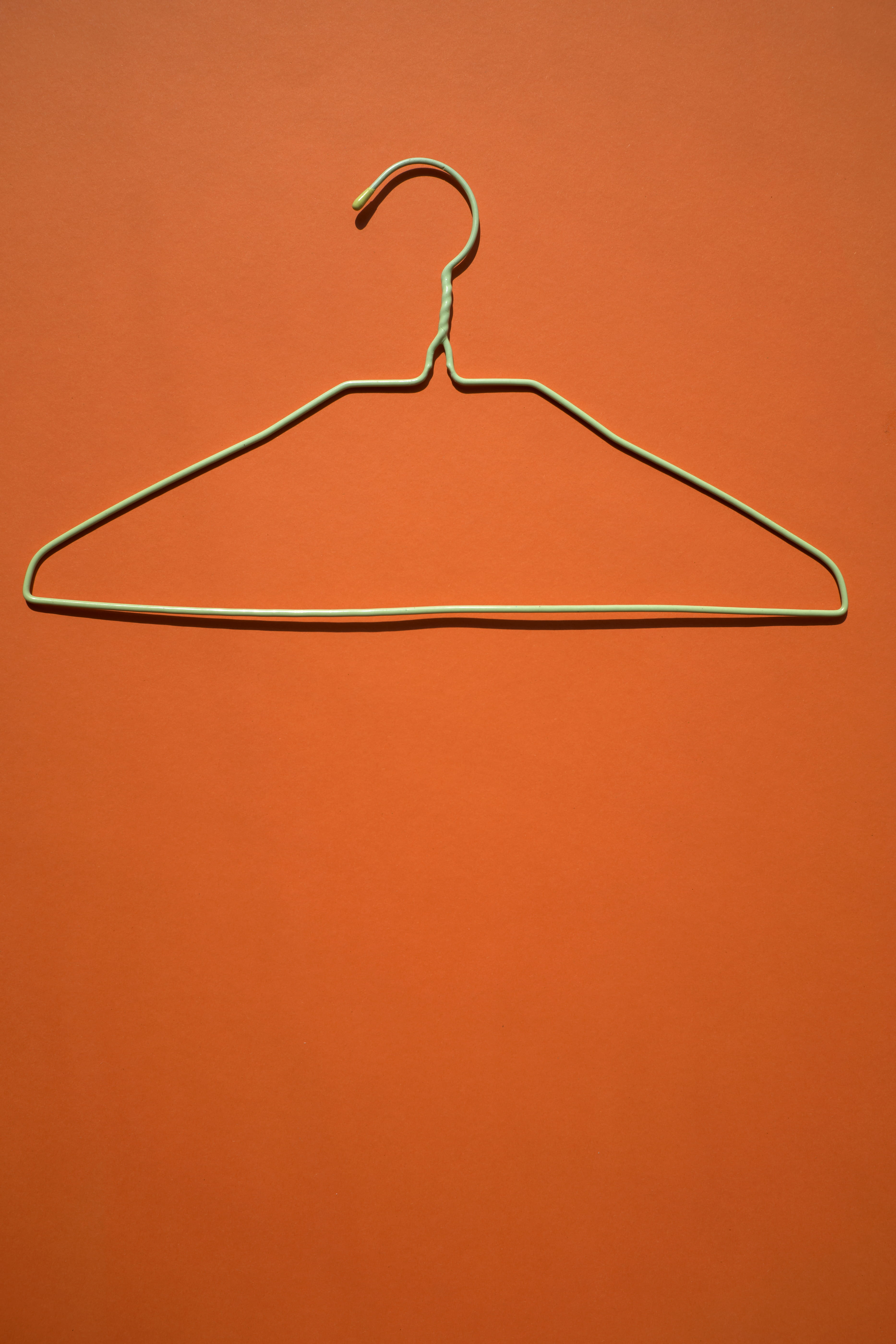 white clothes hanger on orange flooring, closeup photo of gray clothes hanger