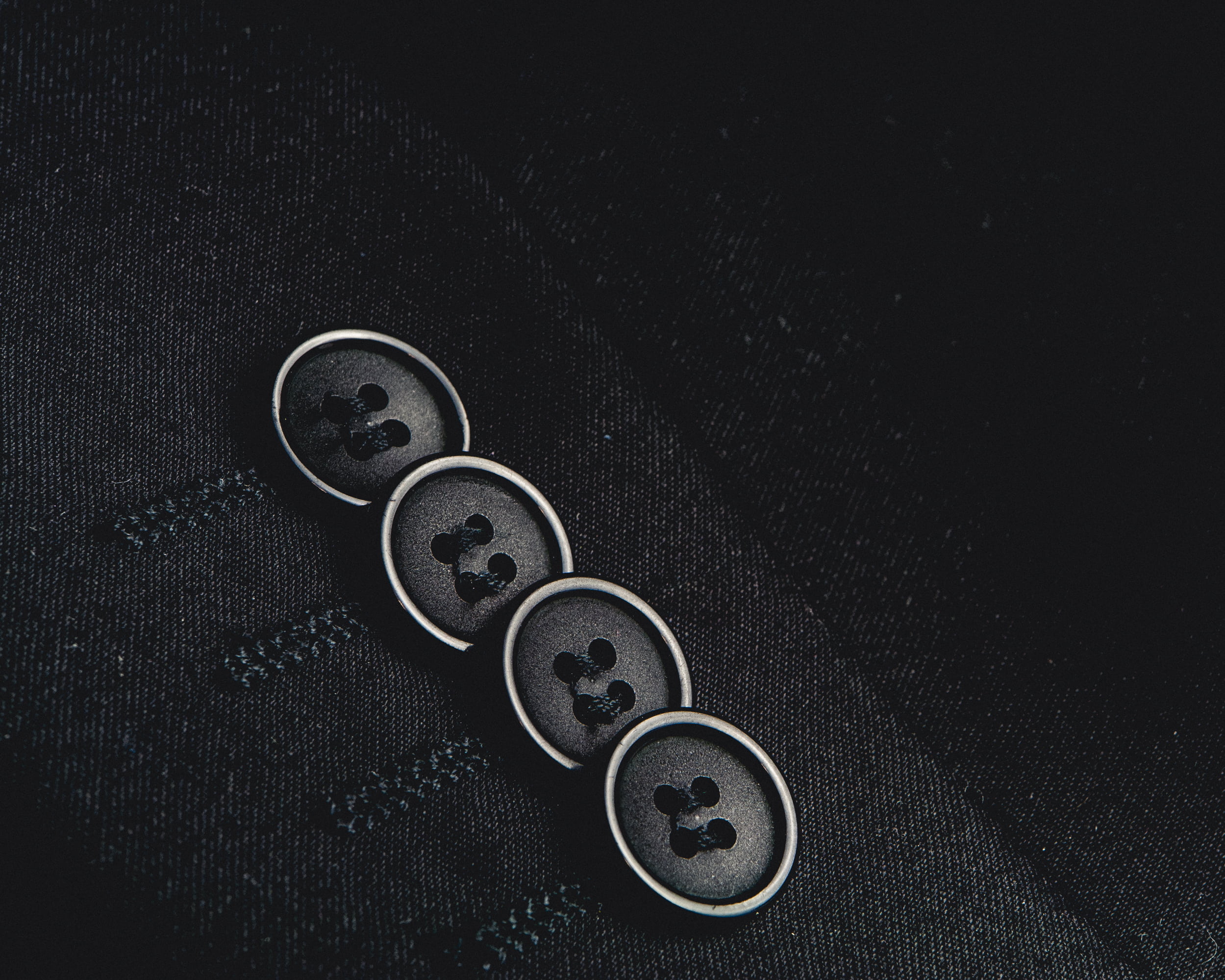 close-up photo of four black shirt buttons, suit, blazer, fashion