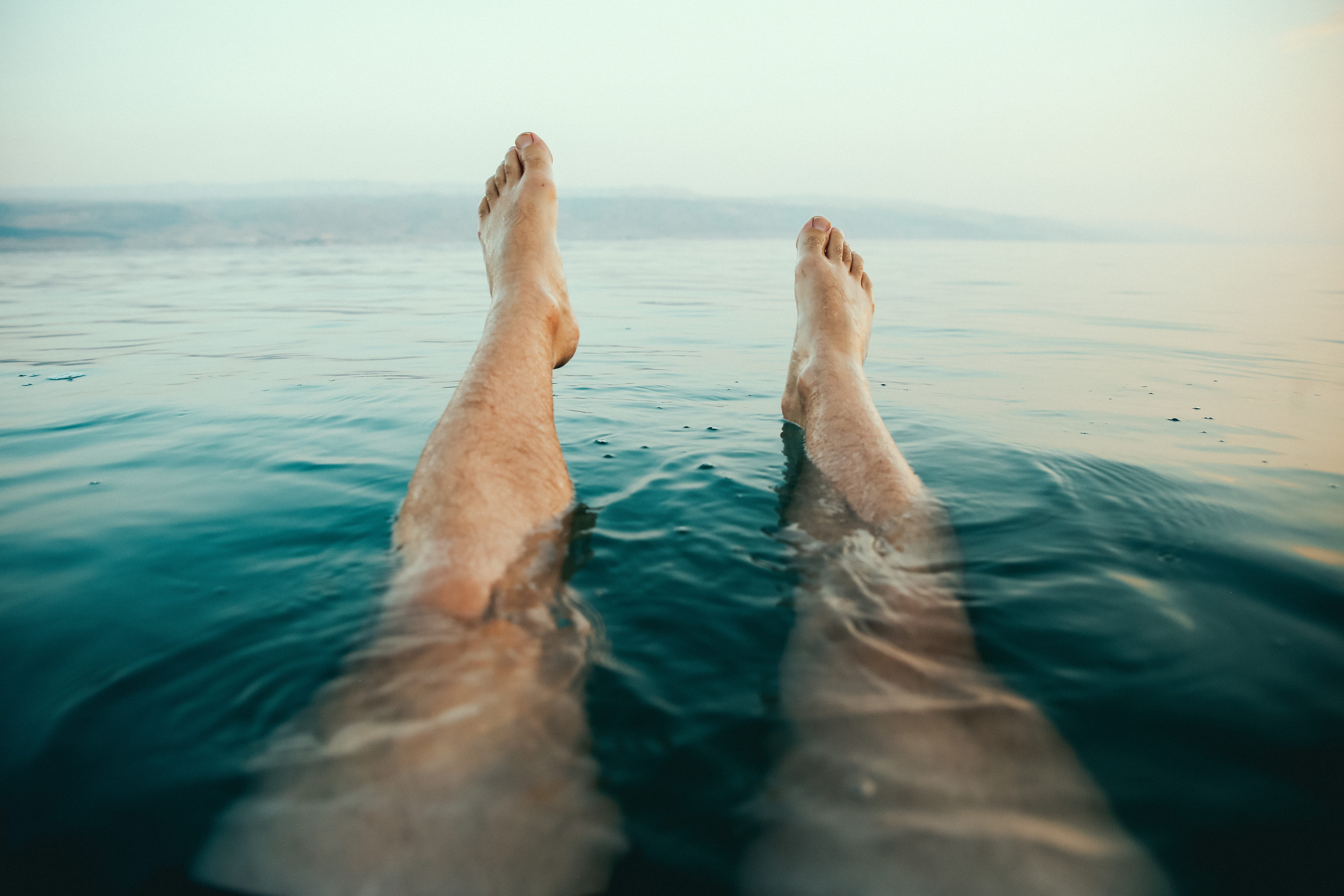 person's legs on water, person's feet above water at daytime