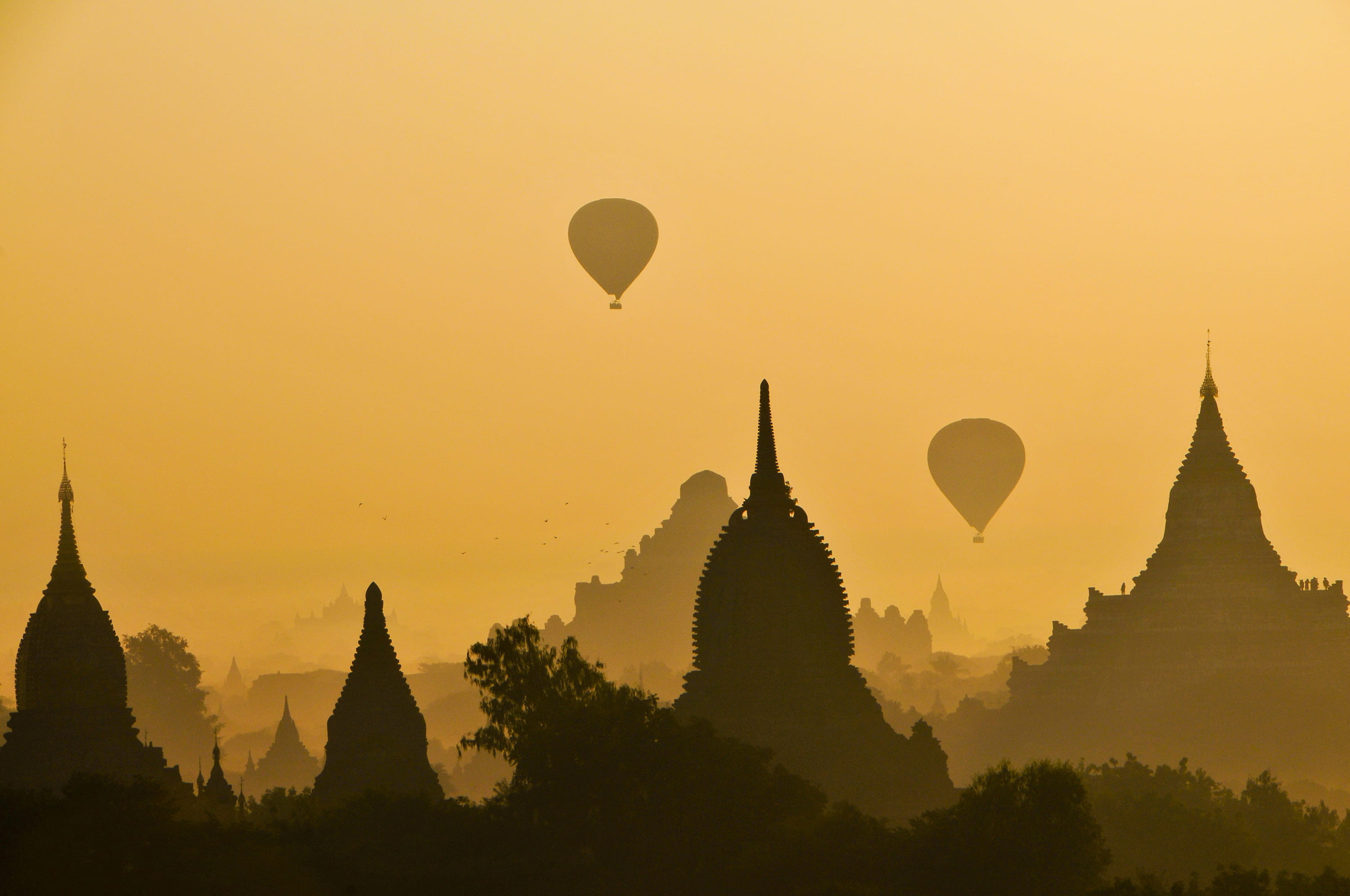 silhouette of two hot air balloons near temple, silhouette photography of two hot air balloons on four towers