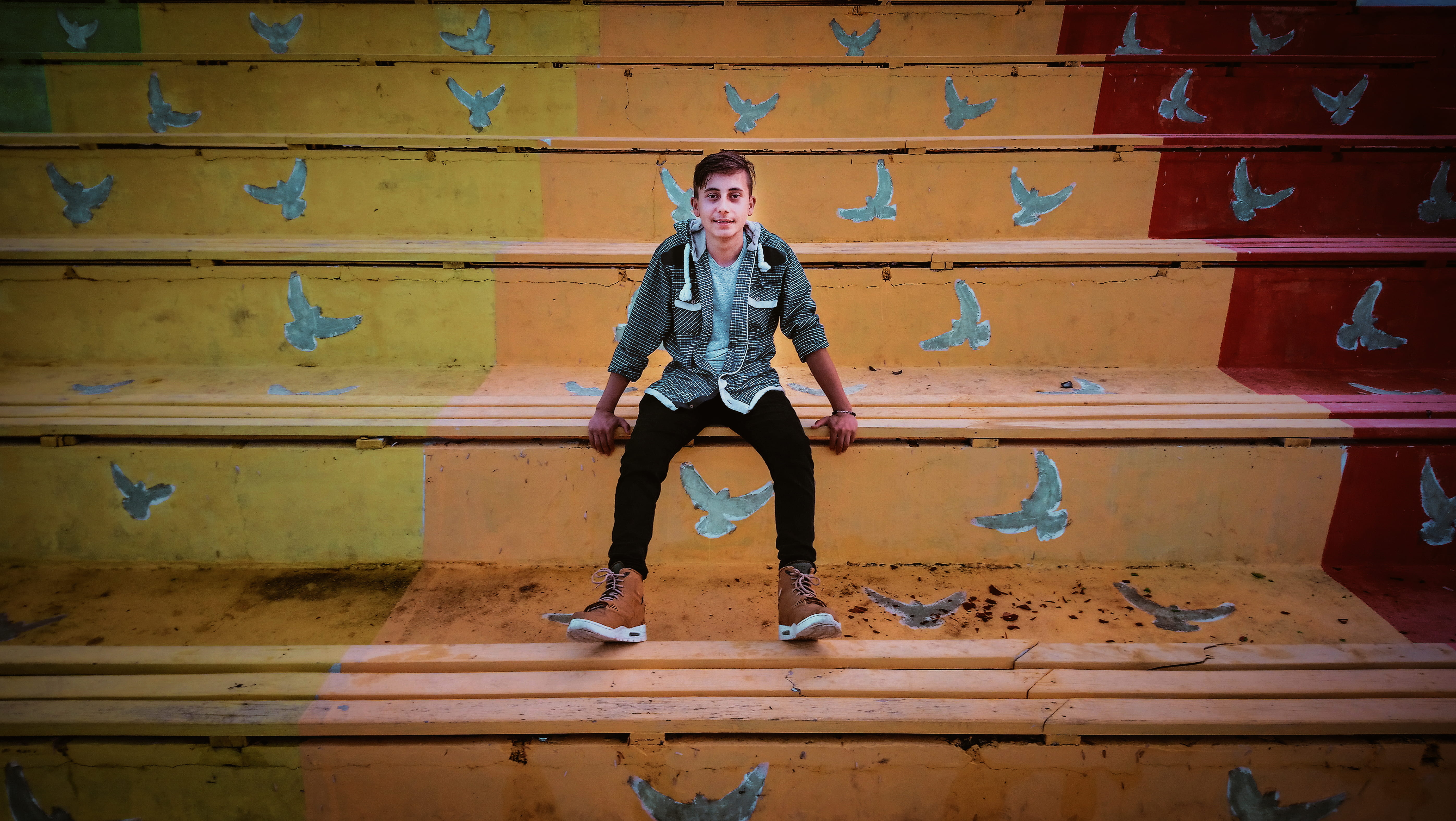 Man in Grey Zip-Up Hoodie And Black Fitted Jeans Sitting, colorful