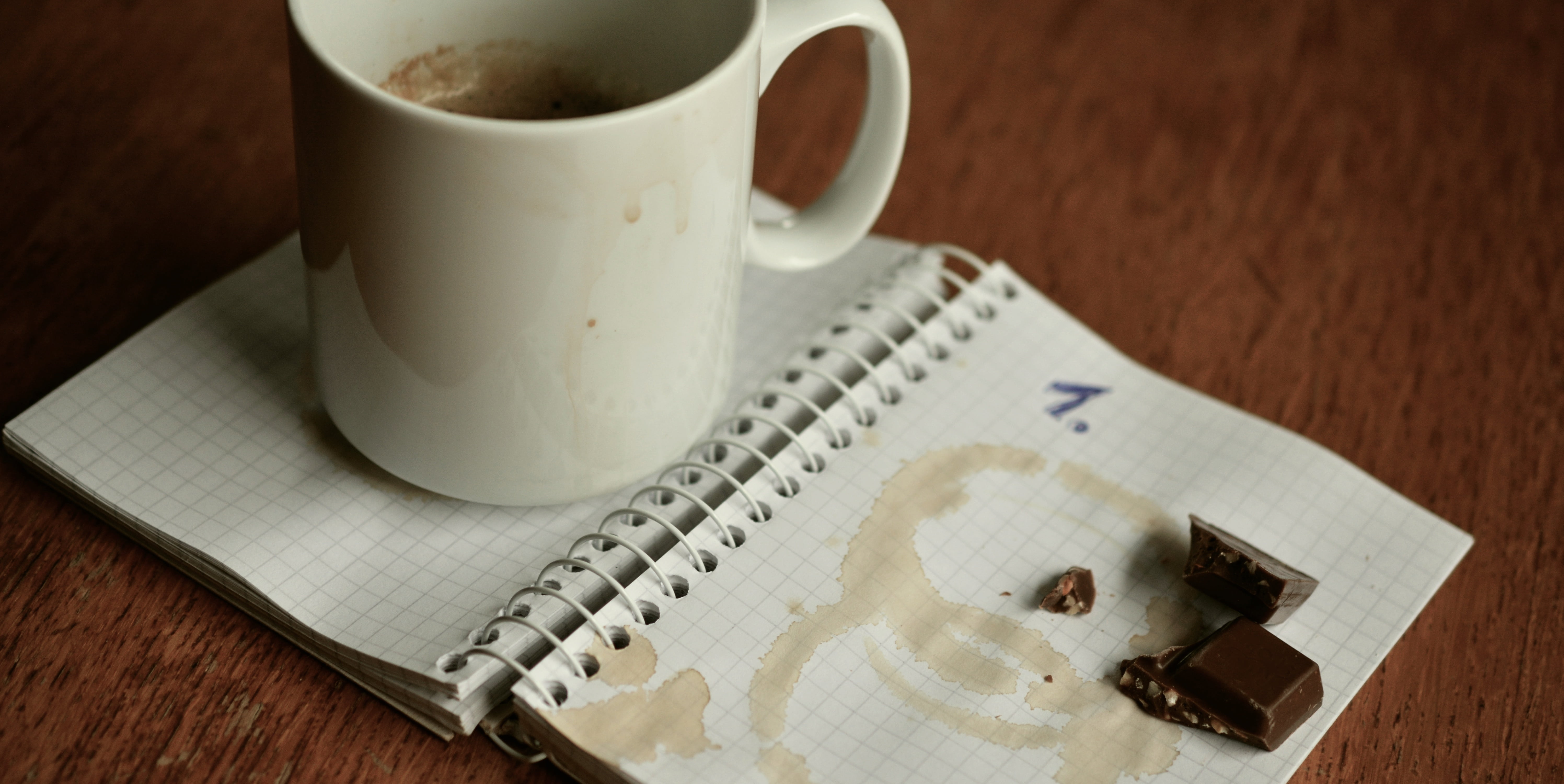 white ceramic mug and chocolate placed on notebook page, plan