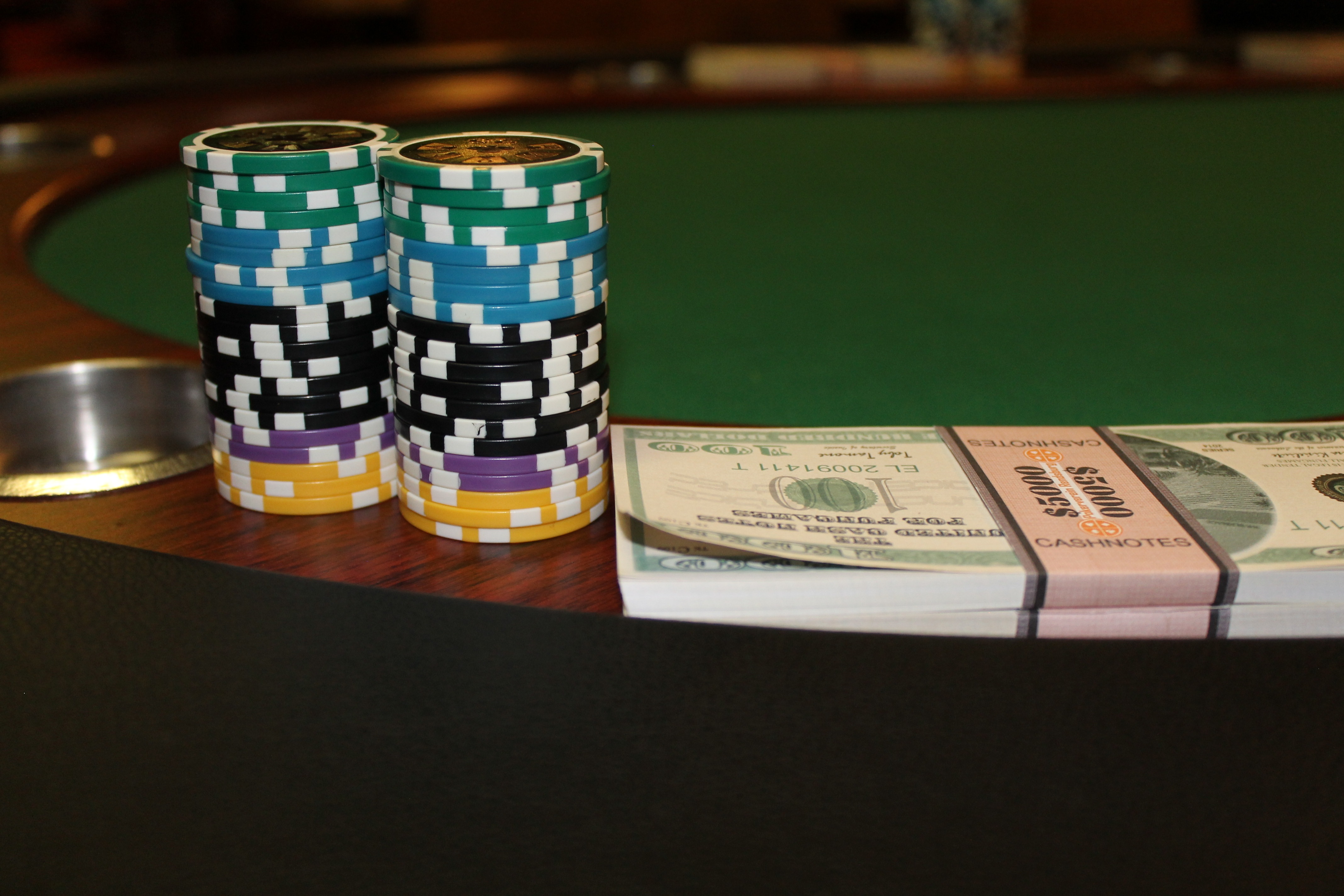 stack of poker chips beside bundle of banknotes on table, casino