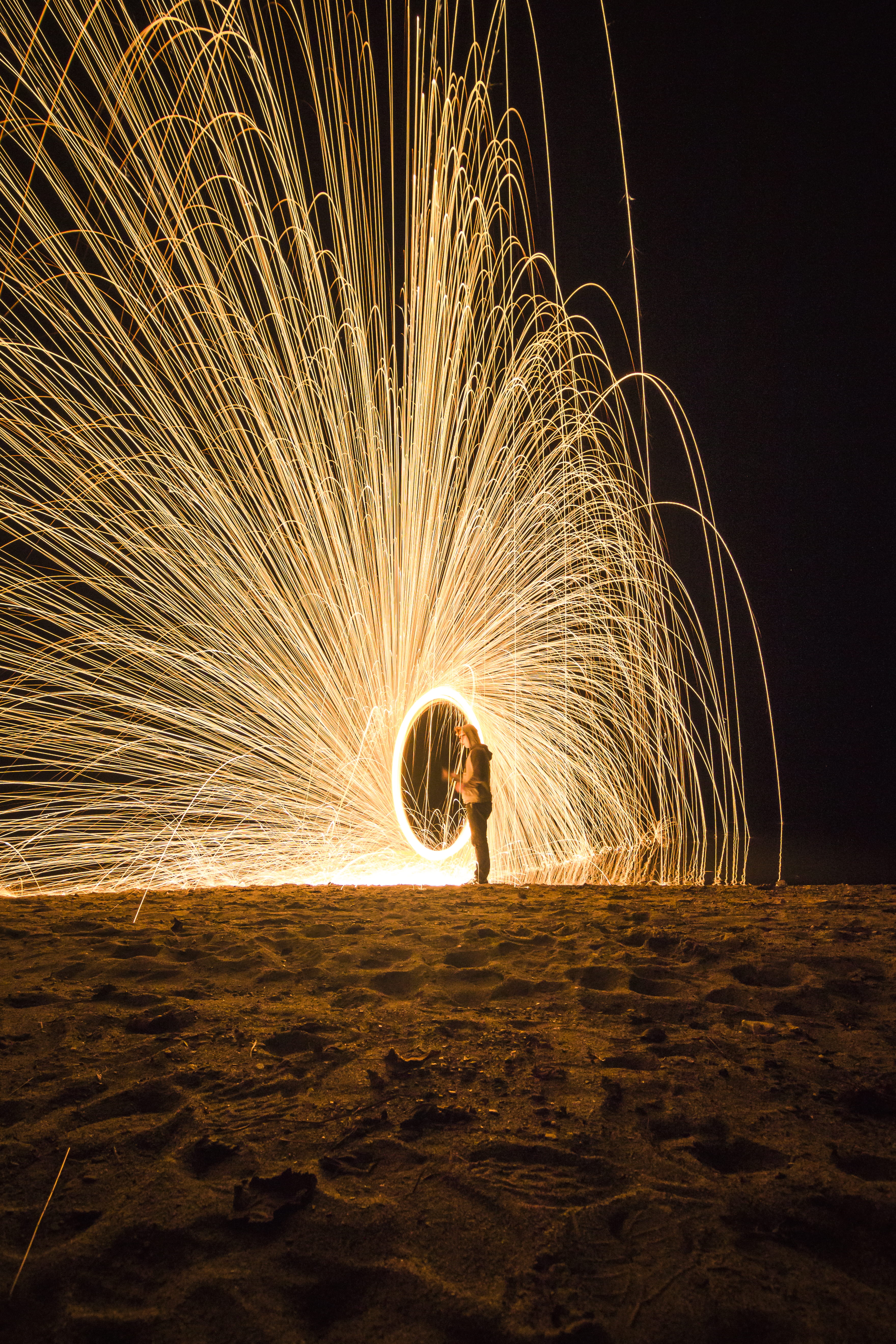 person holding fireworks on beach during nighttime, lights, spark
