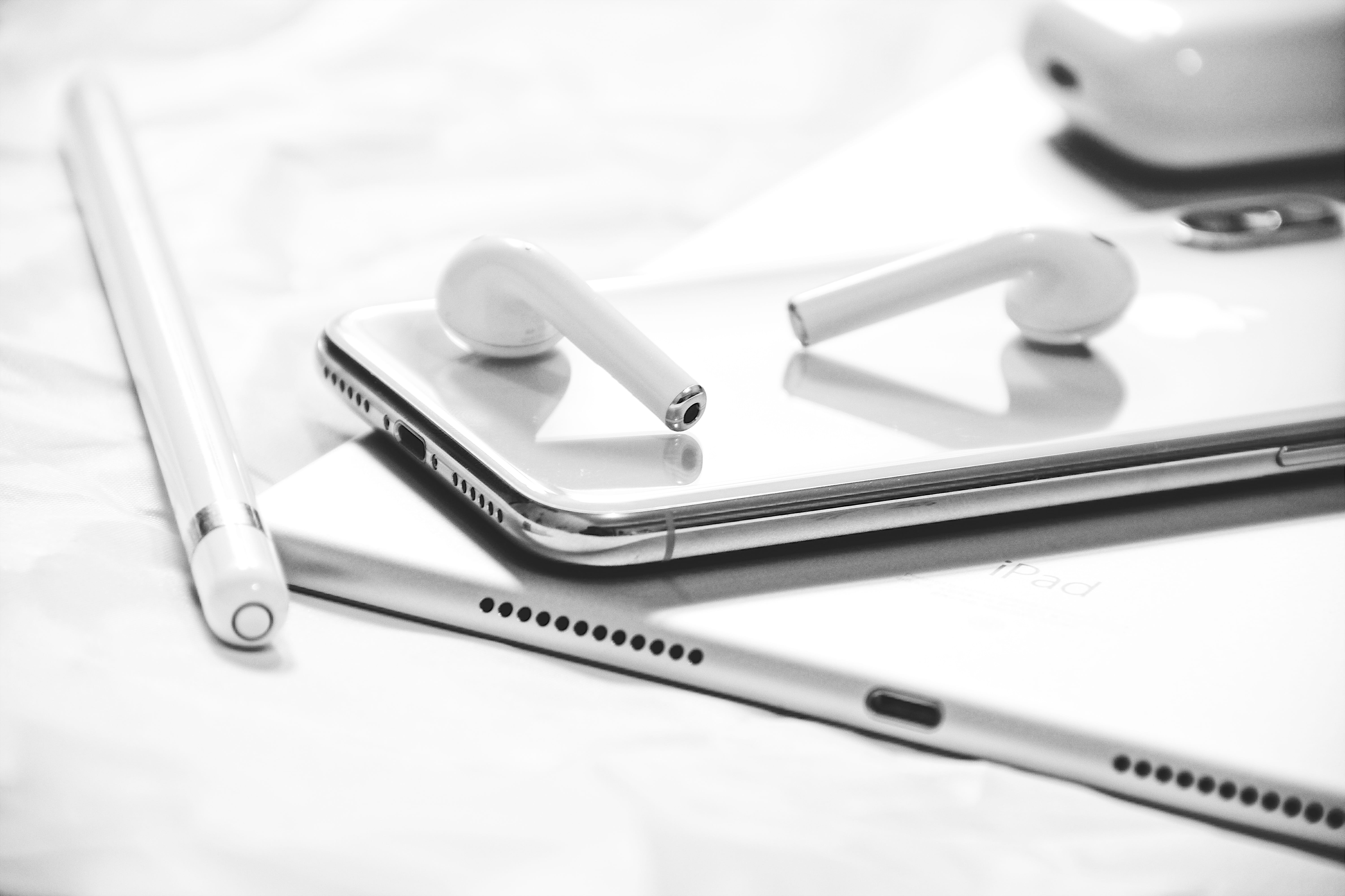 grayscale photography of iPhone X, AirPods, Apple Pencil and iPad, silver iPhone X with Apple Pencil and AirPods