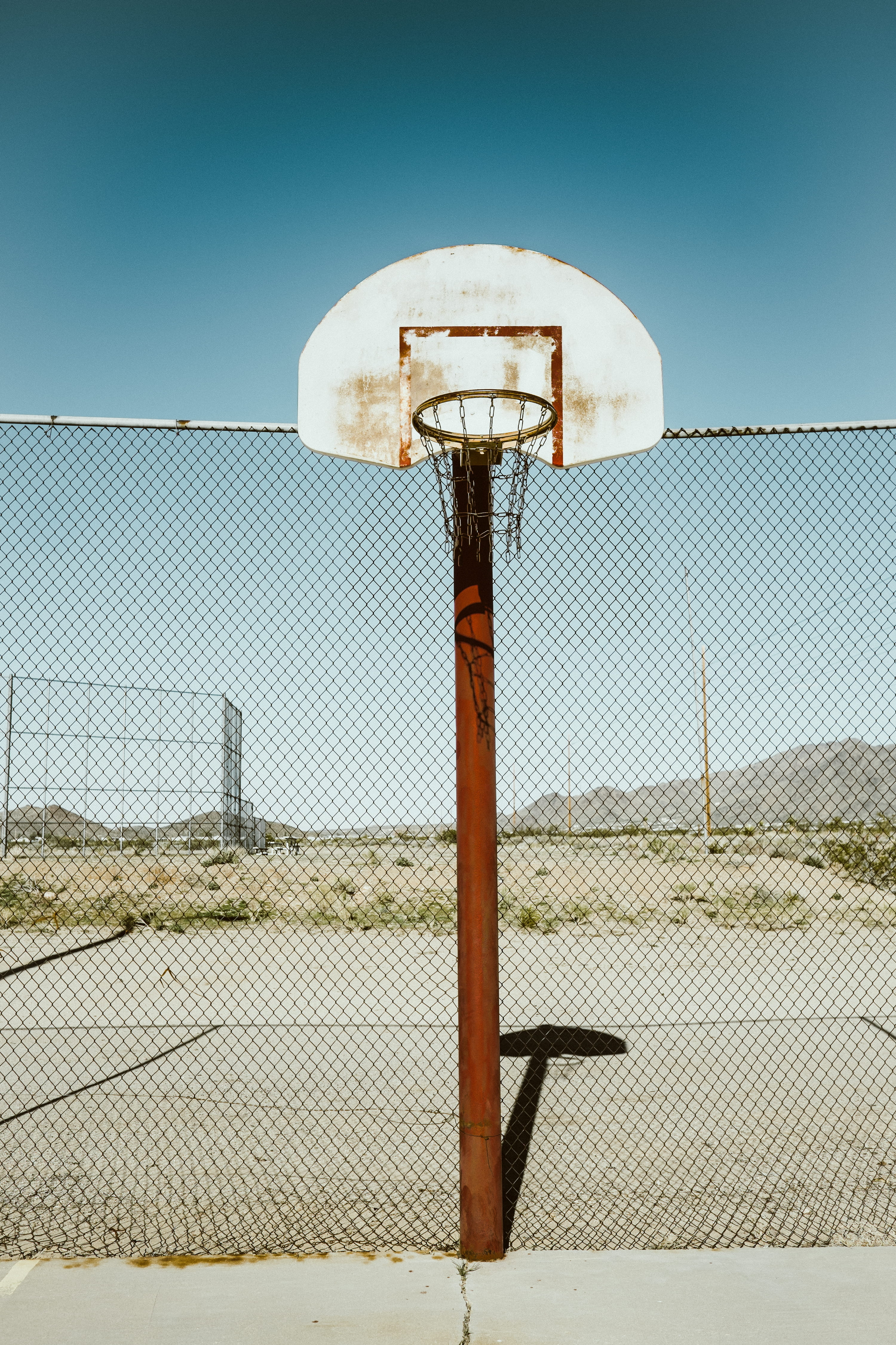 white and brown basketball hoop, portable basketball near chain link fence