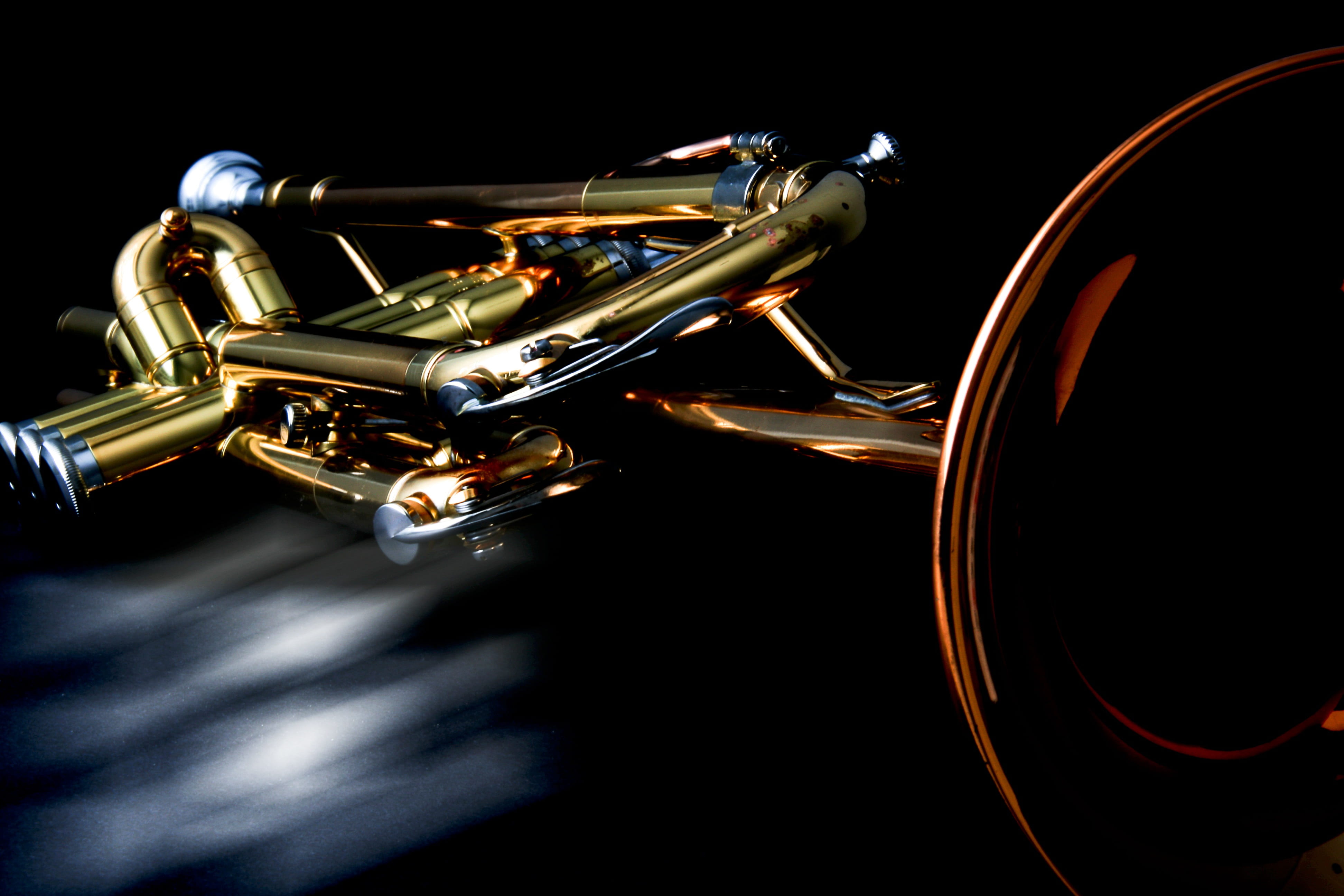 low-light closeup photo of brass-colored trumpet, musical instrument