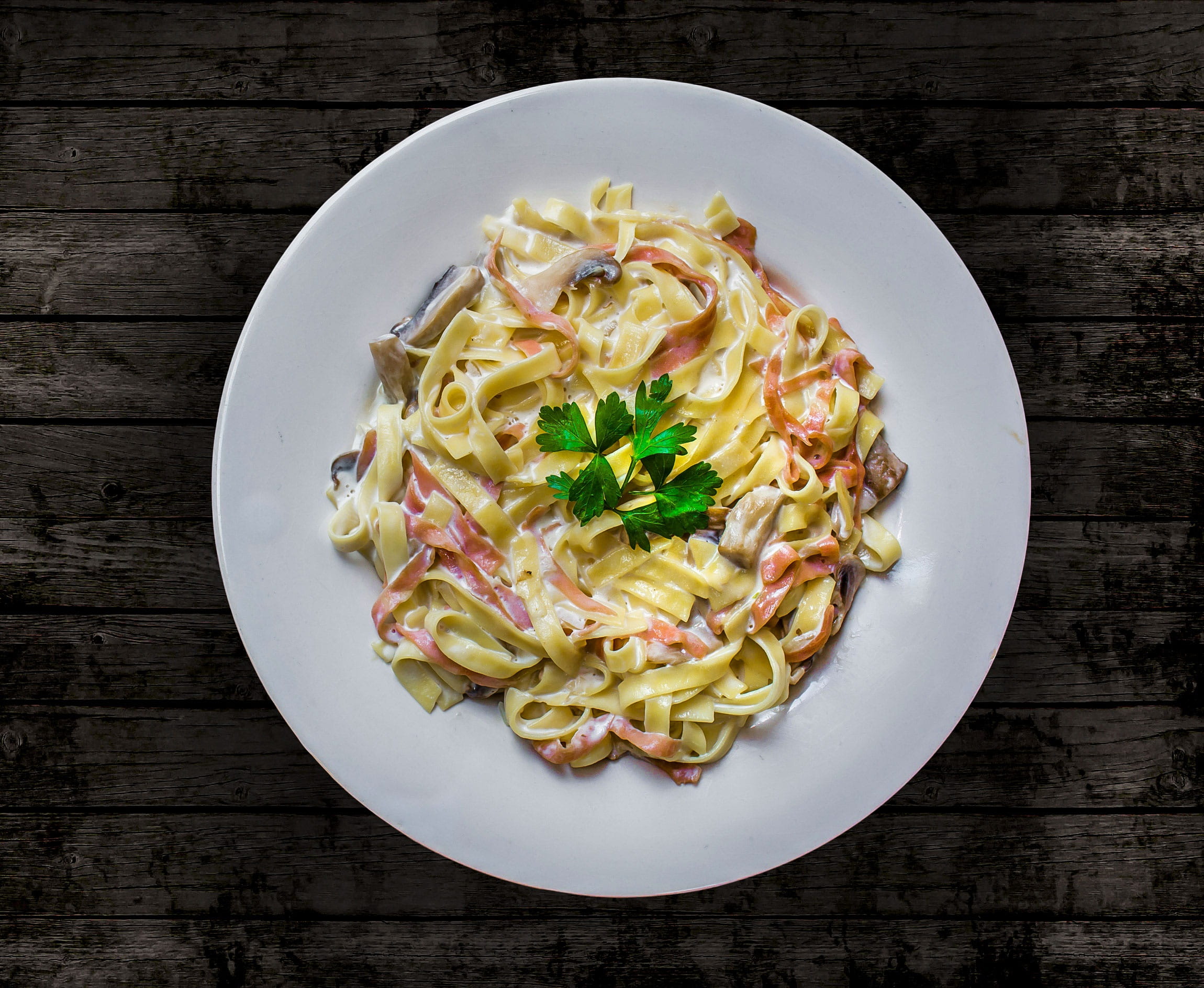 pasta on round plate on brown wooden table, Carbonara, white