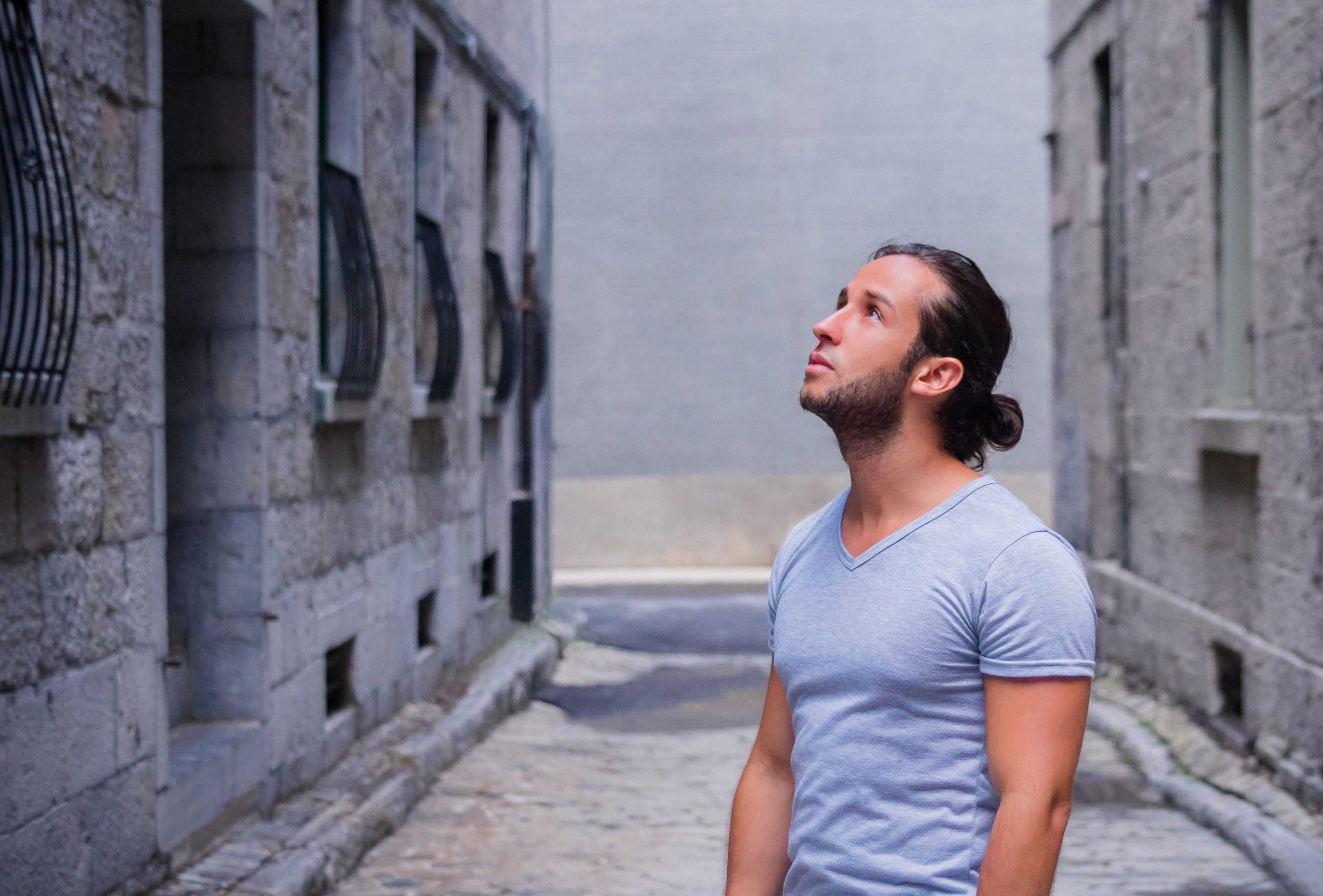 person in gray V-neck T-shirt standing near gray concrete buildings