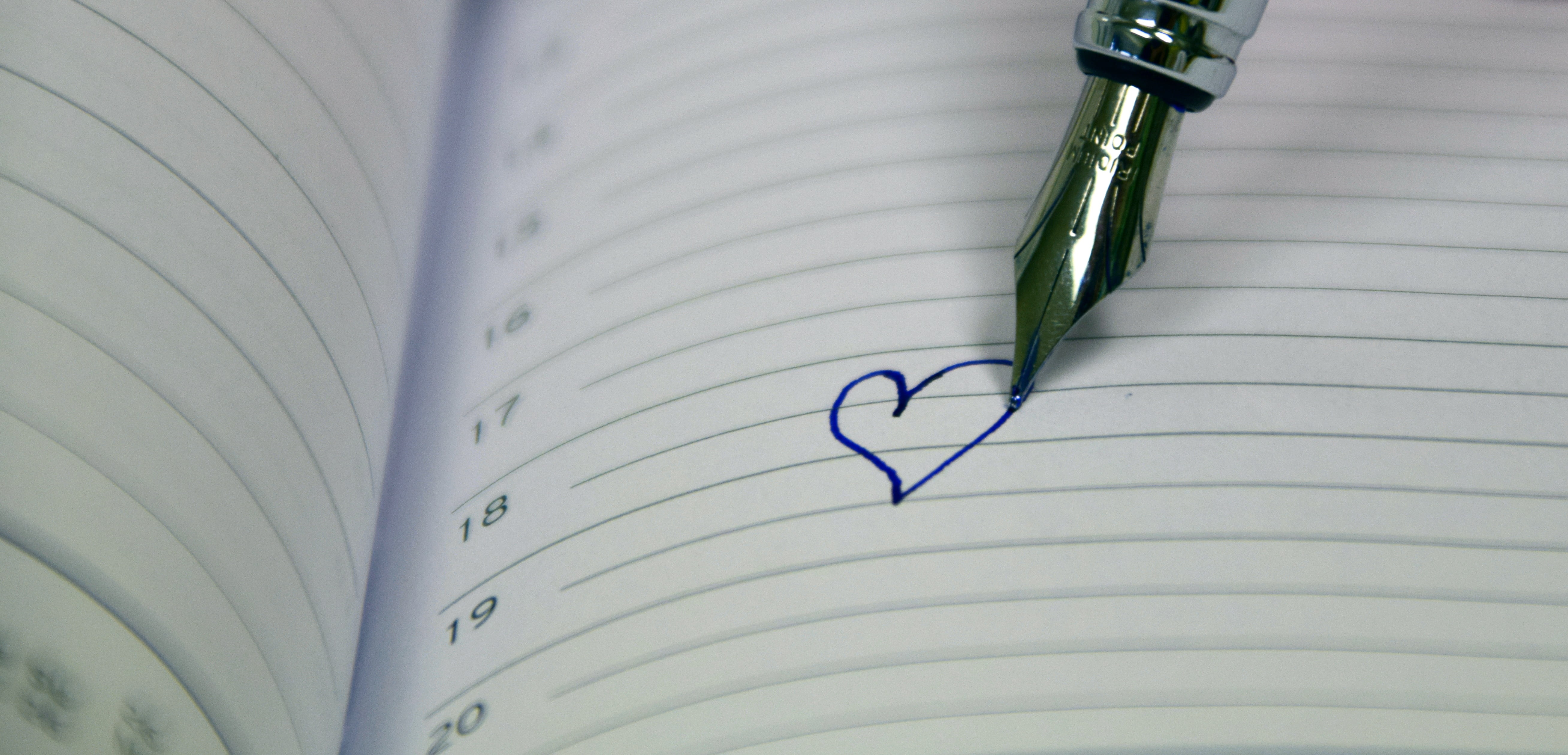 silver fountain pen drew a heart in white ruled paper, book, calendar
