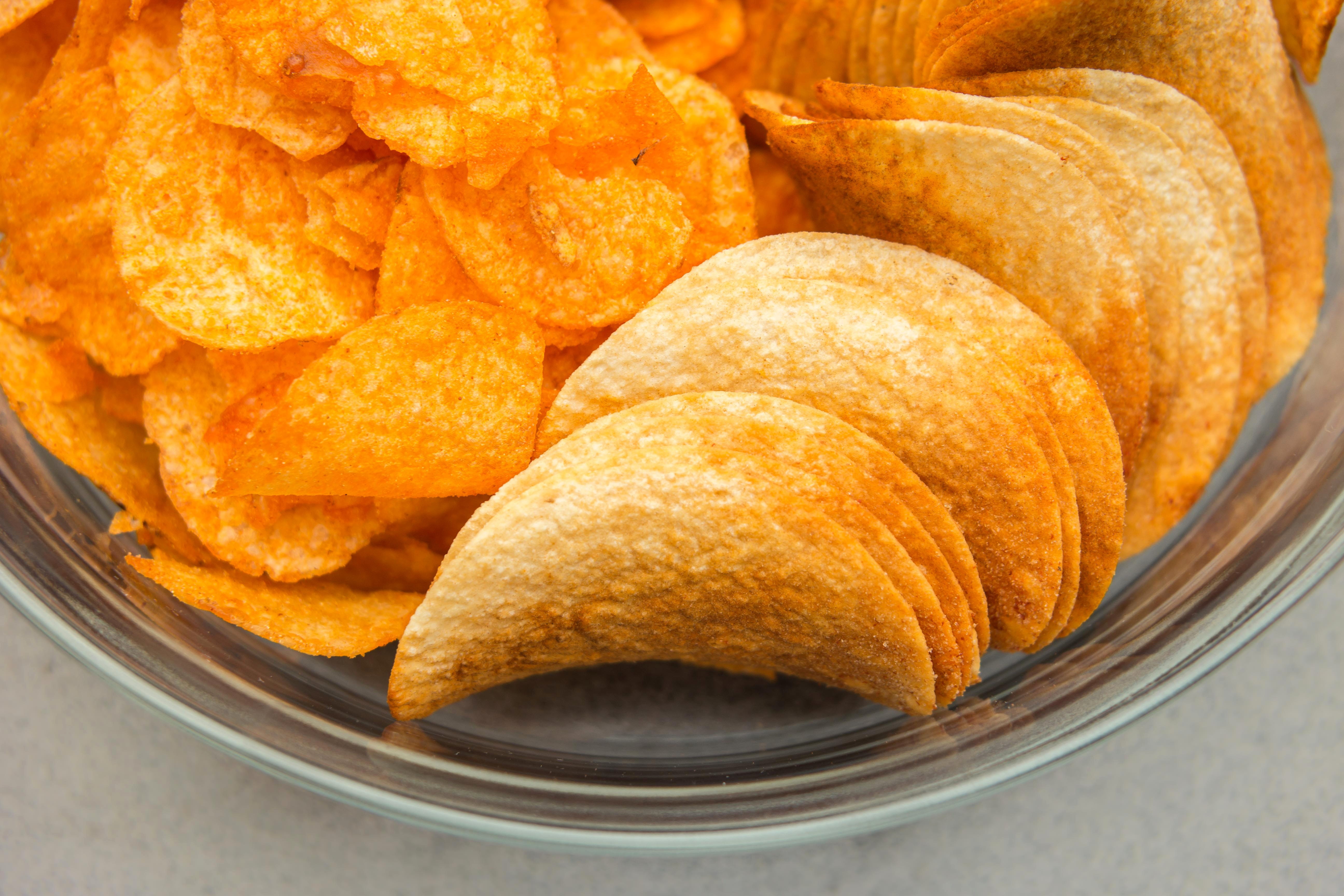 closeup photo of chips on clear glass bowl, snack, pringles, crisps