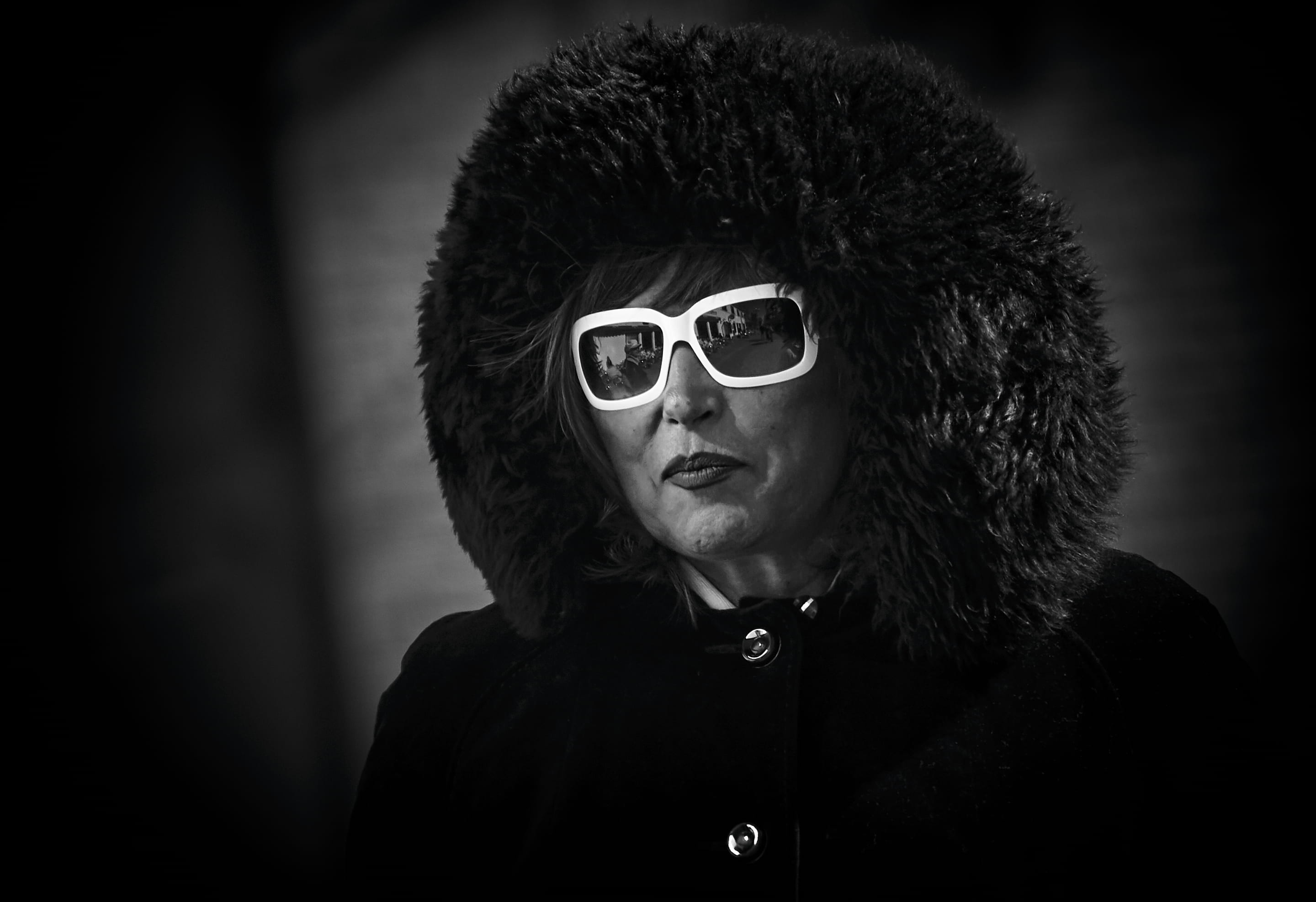 selective color of woman wearing white framed sunglasses, grayscale photo of woman wearing fur jacket