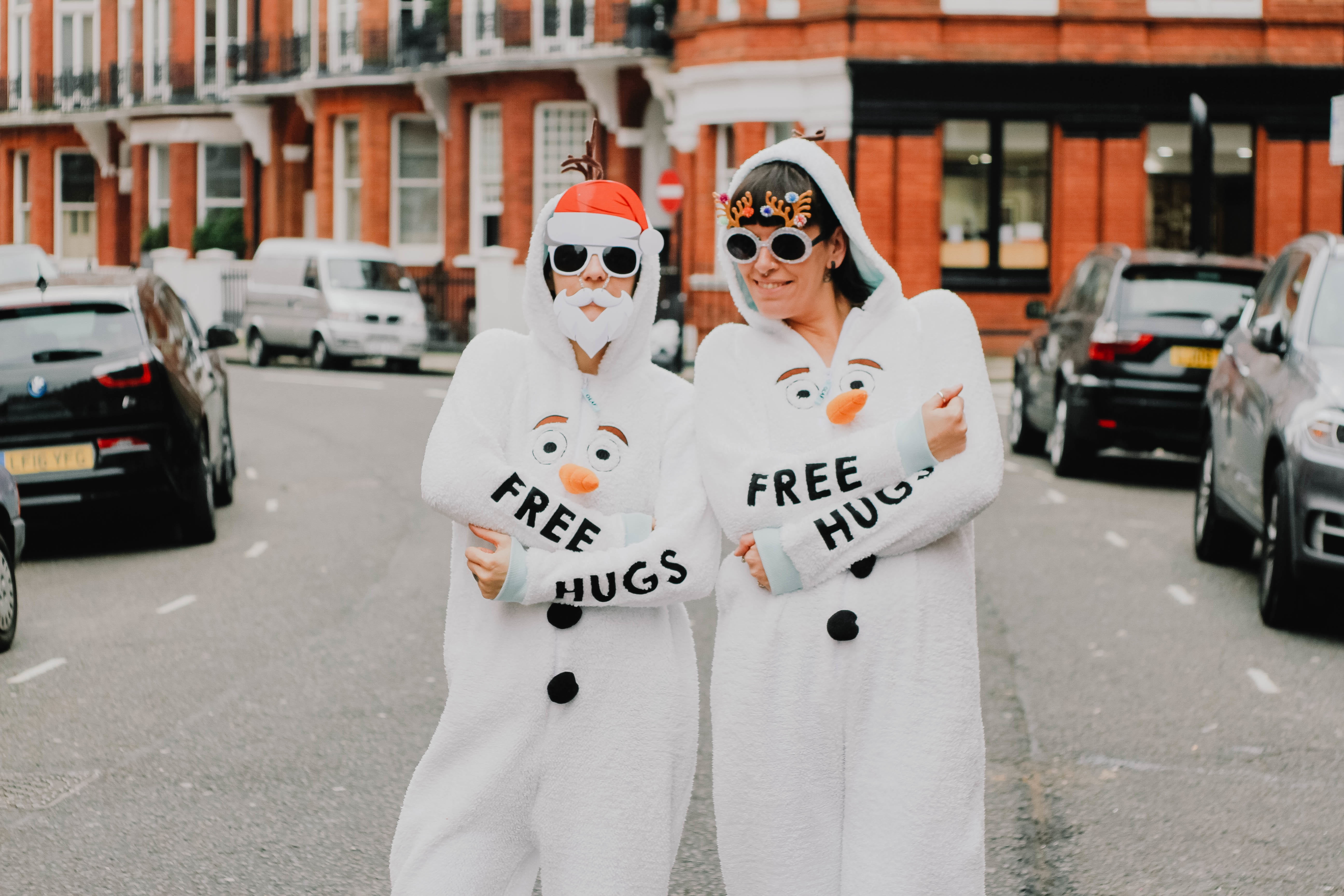 two people in snowman costumes standing on street, hug, woman