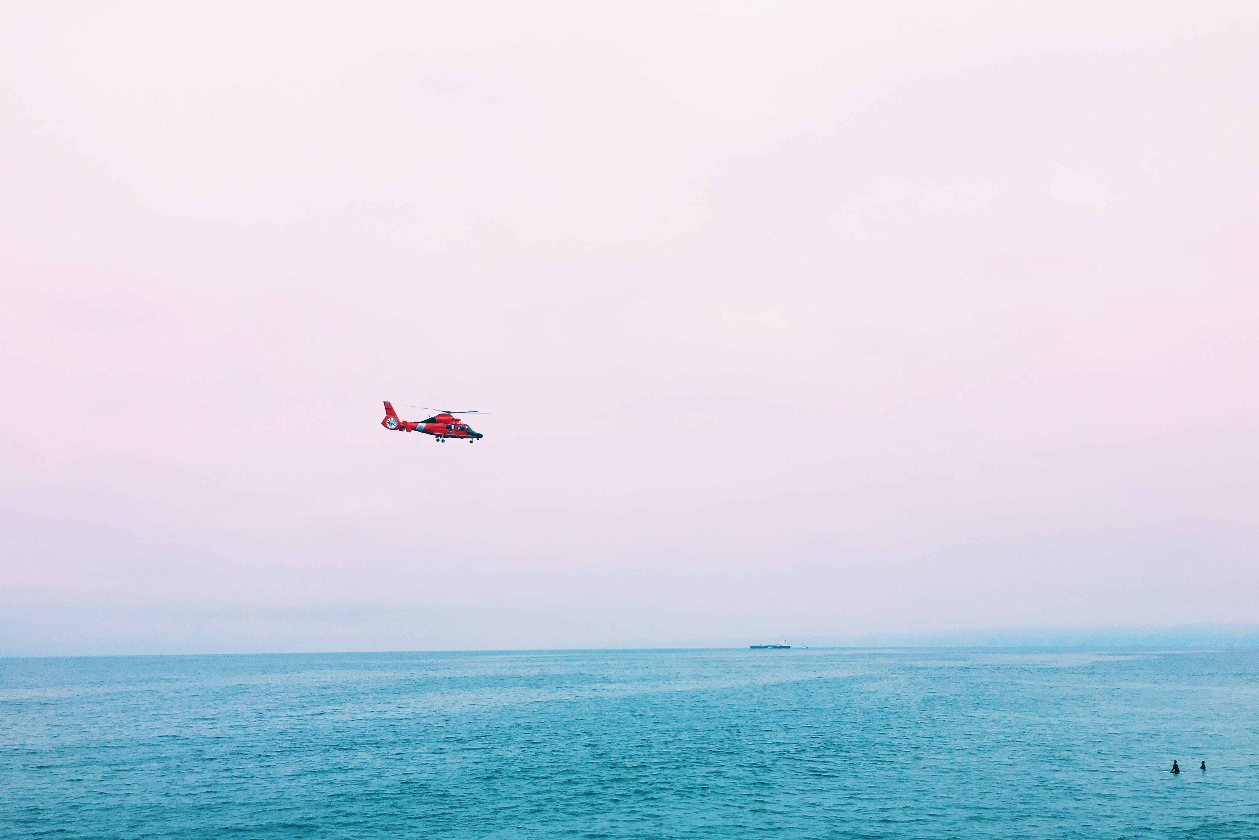 red plane on mid air above sea, flying helicopter above body of water at daytime