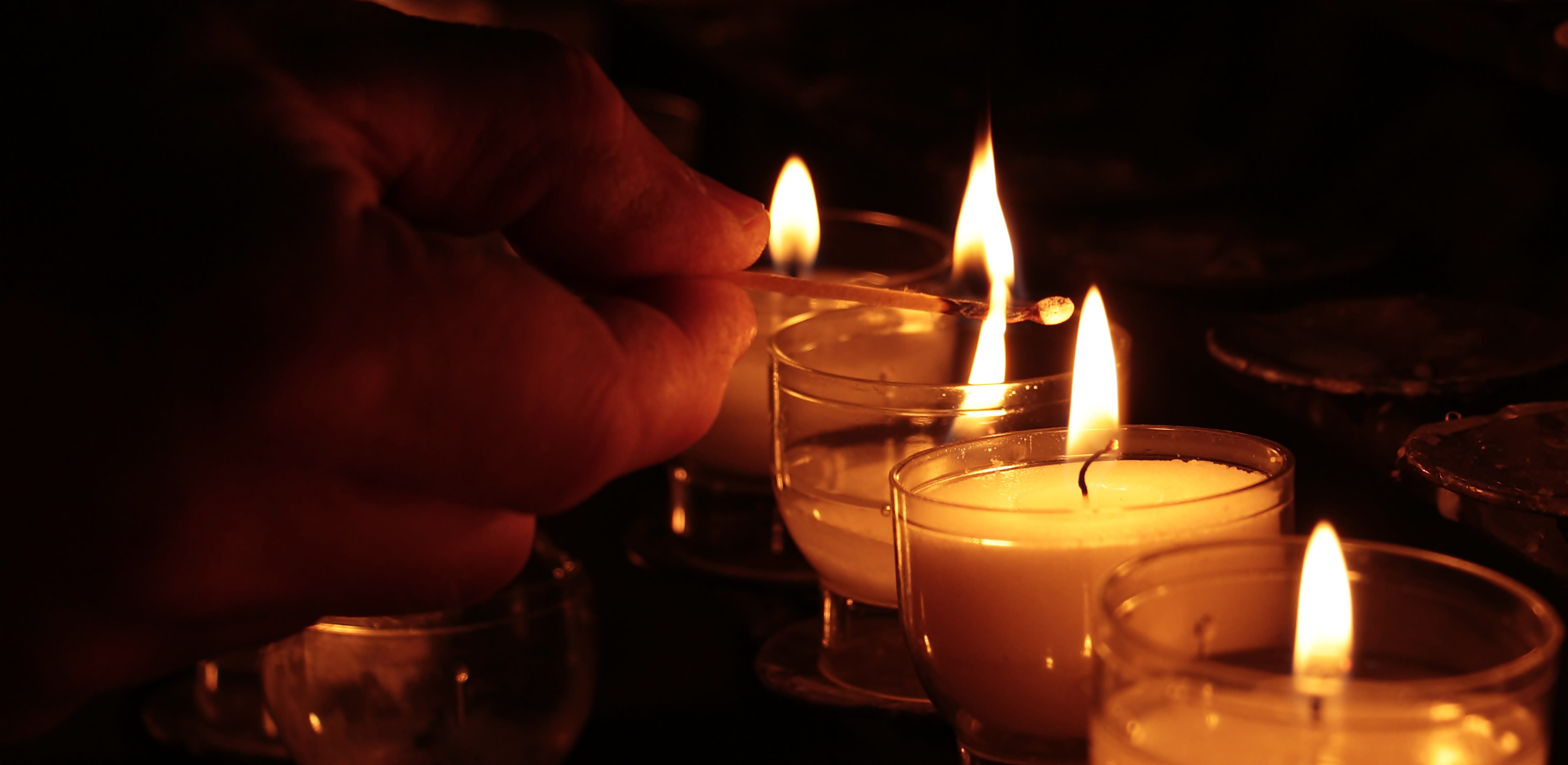person lighting votive candles, tea lights, hand, church, prayer