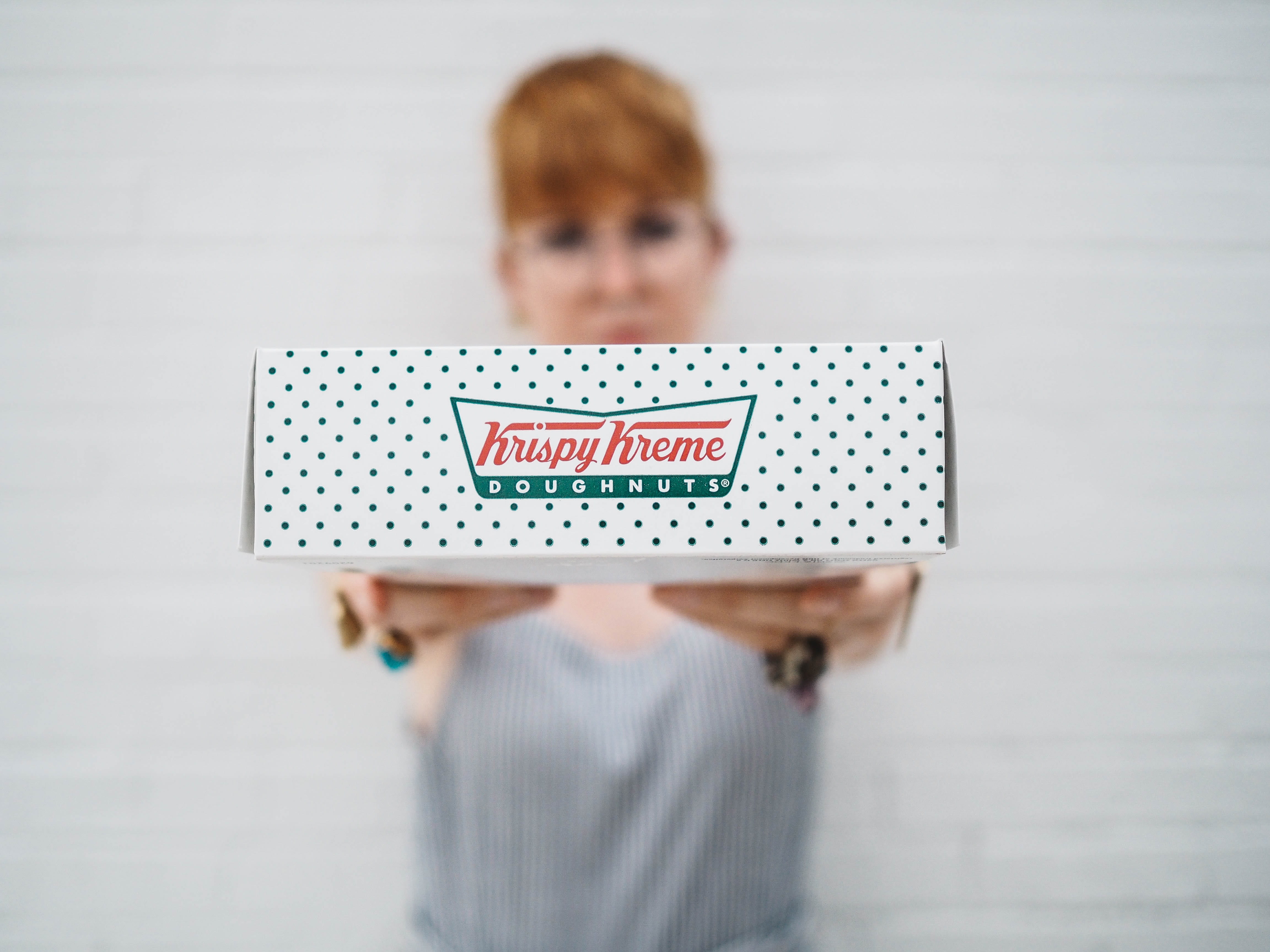 woman showing Krispy Kreme box, person holding Krispy Kreme doughnuts box