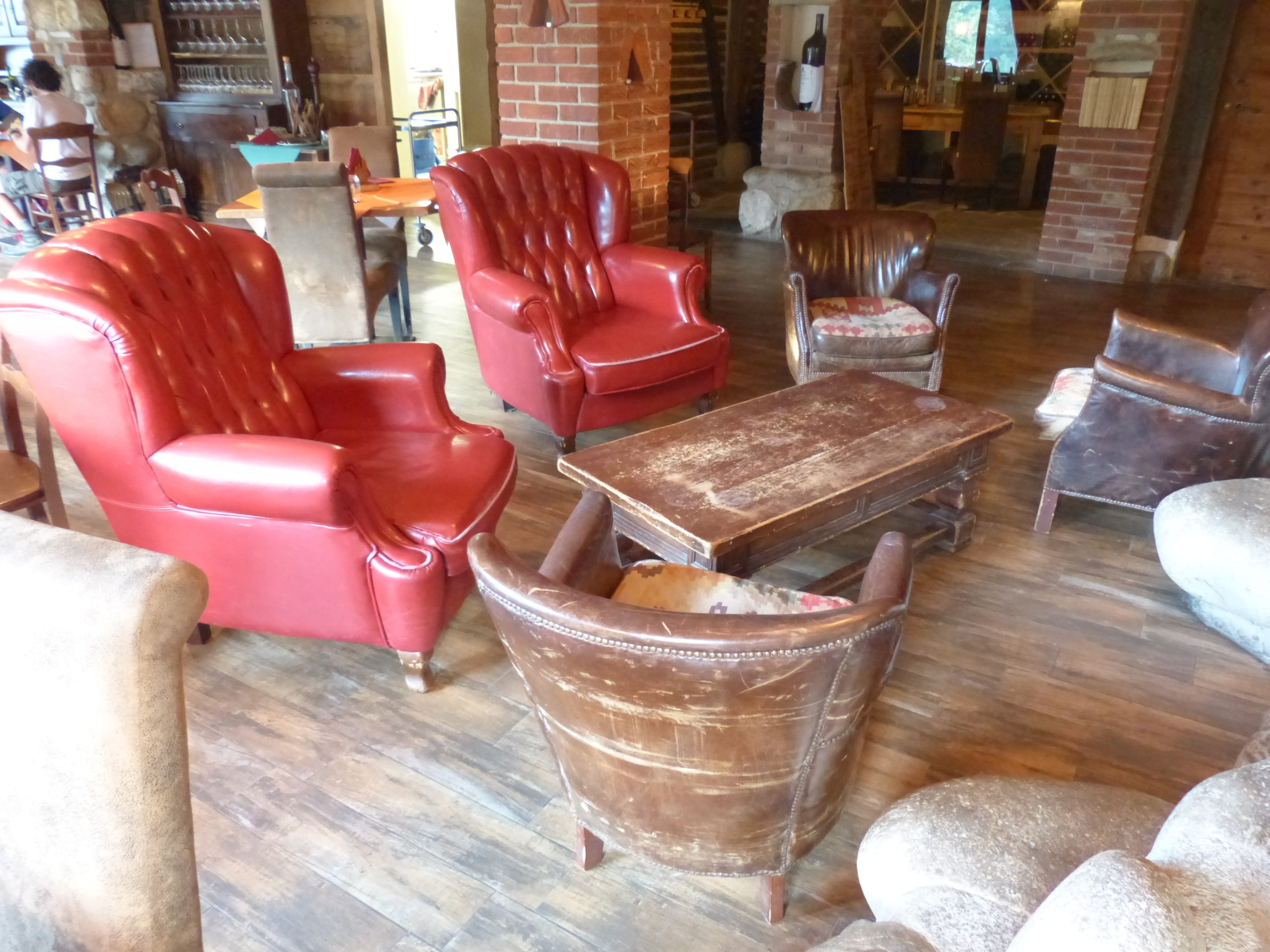 rectangular brown wooden center table beside two red quilted leather wing chairs