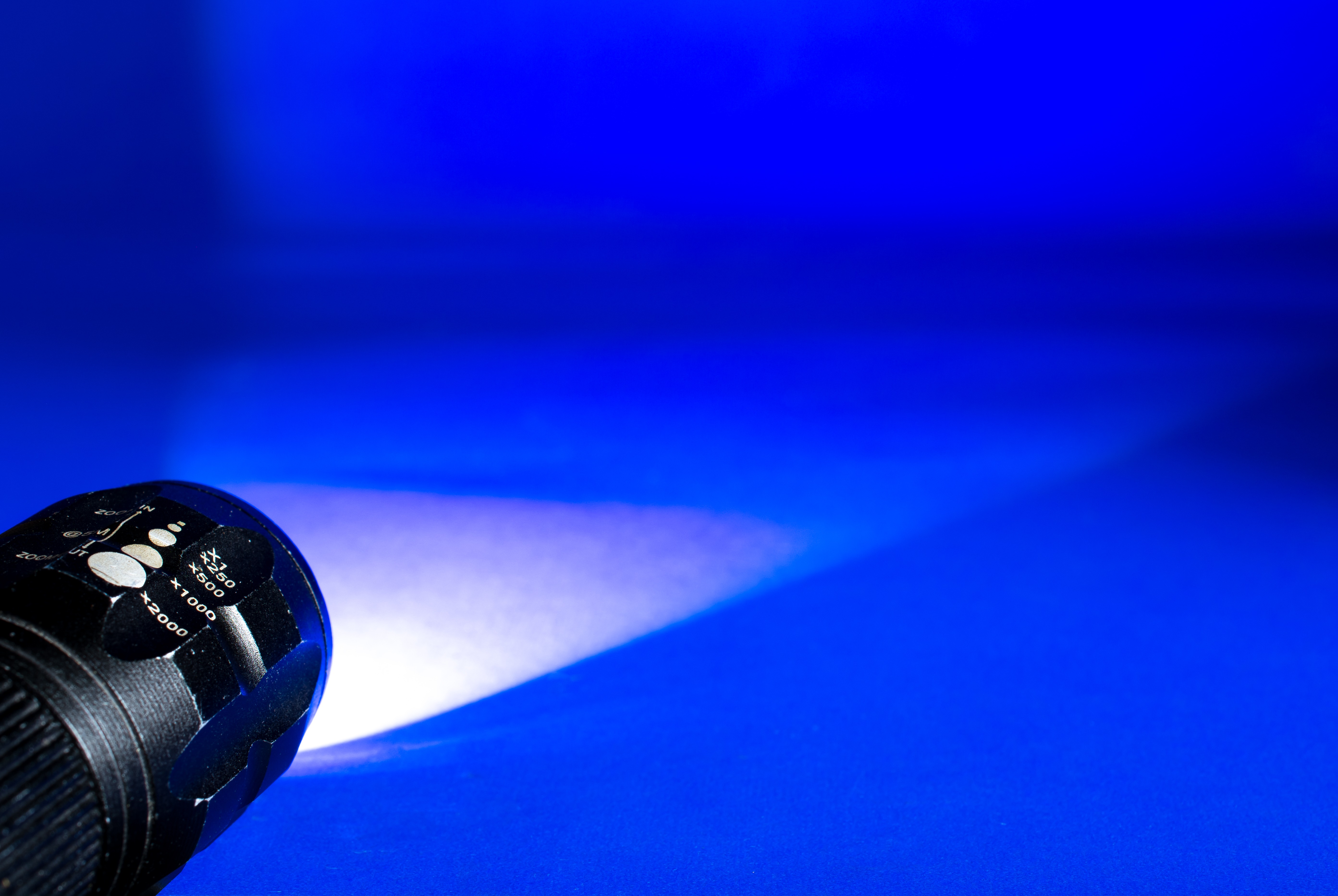 black flashlight on floor, light cone, glow, blue, technology