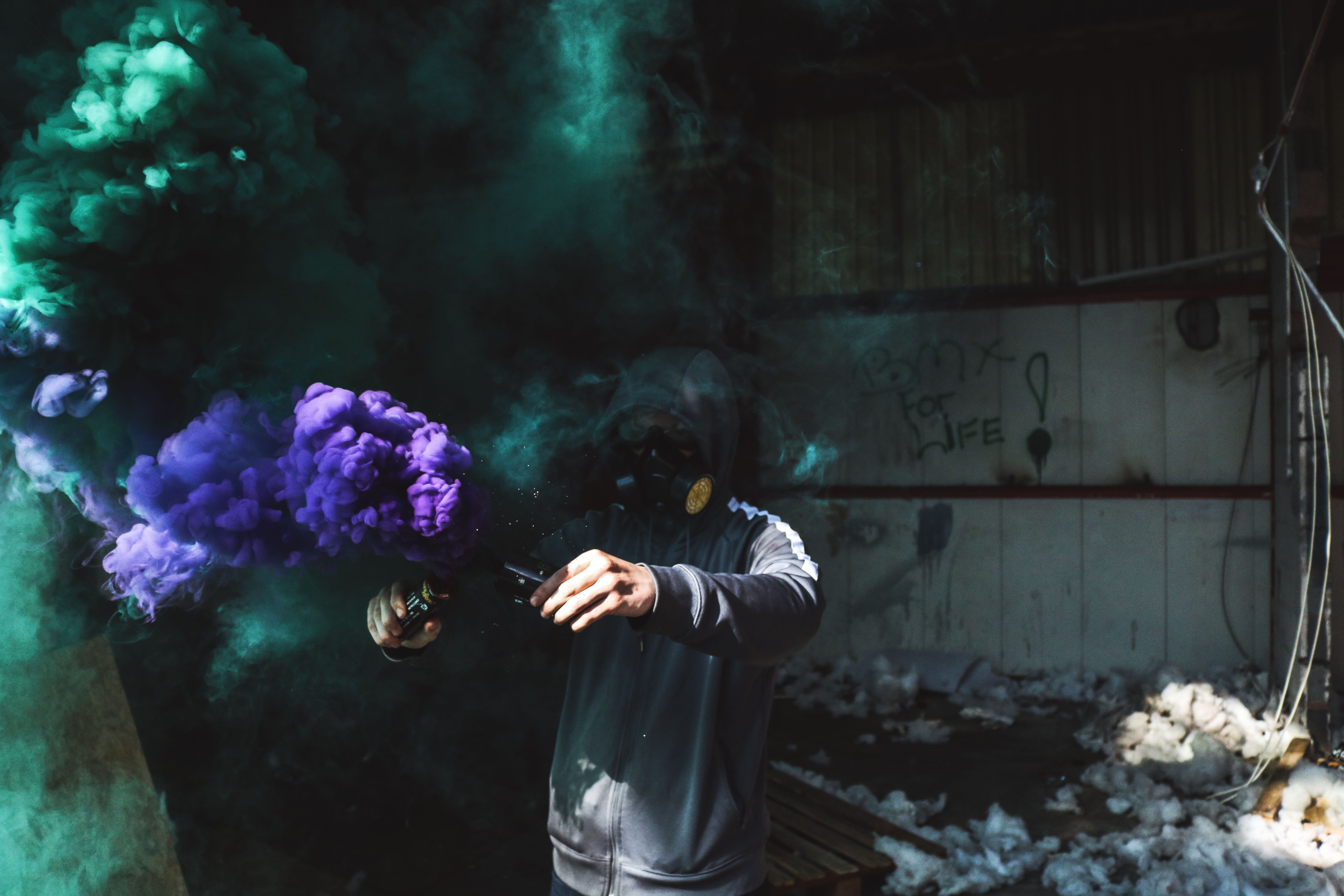 man in black jacket, person using purple and green smoke bomb