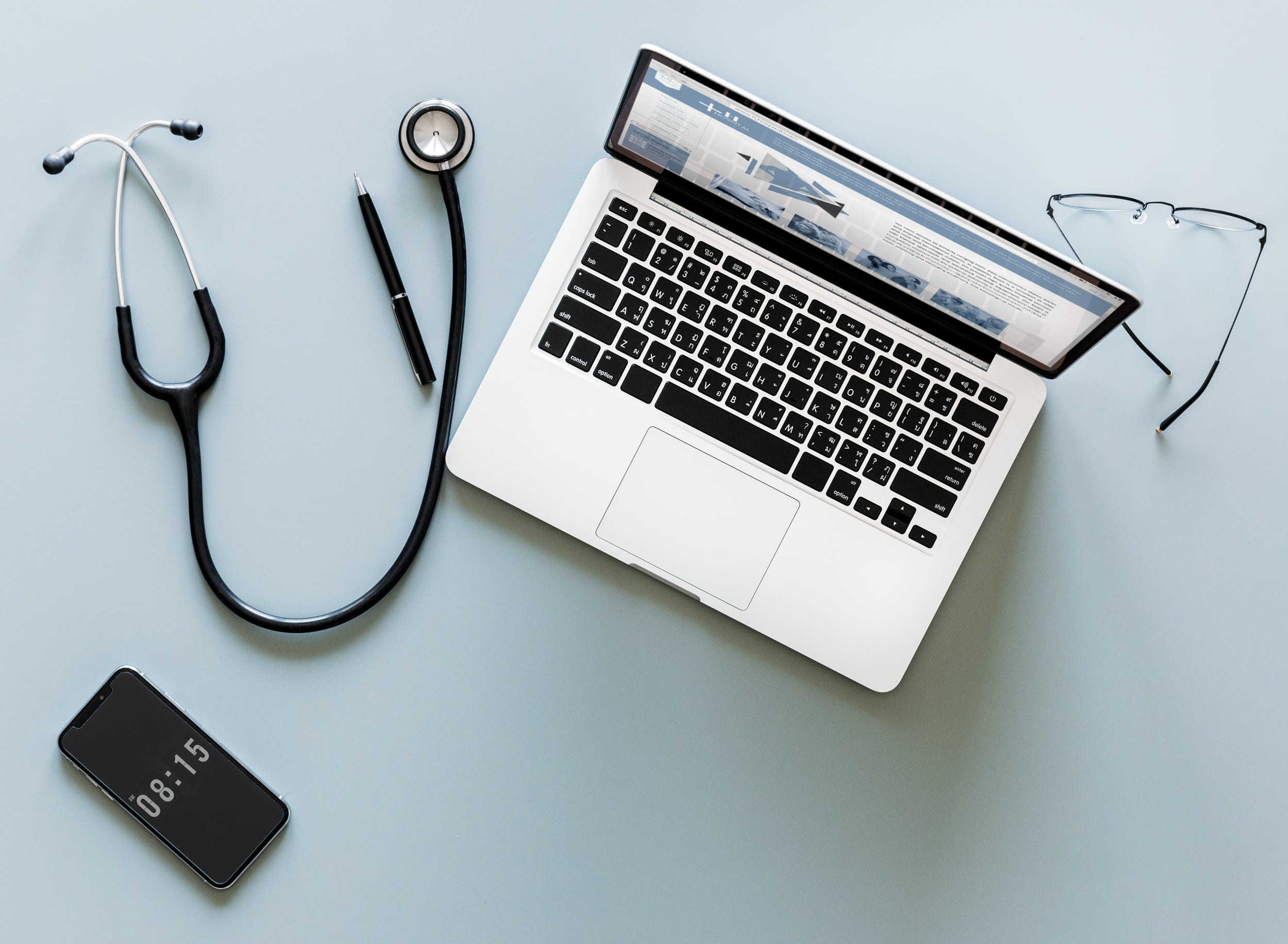 silver MacBook beside stethoscope and pen, aerial, cardiac, care
