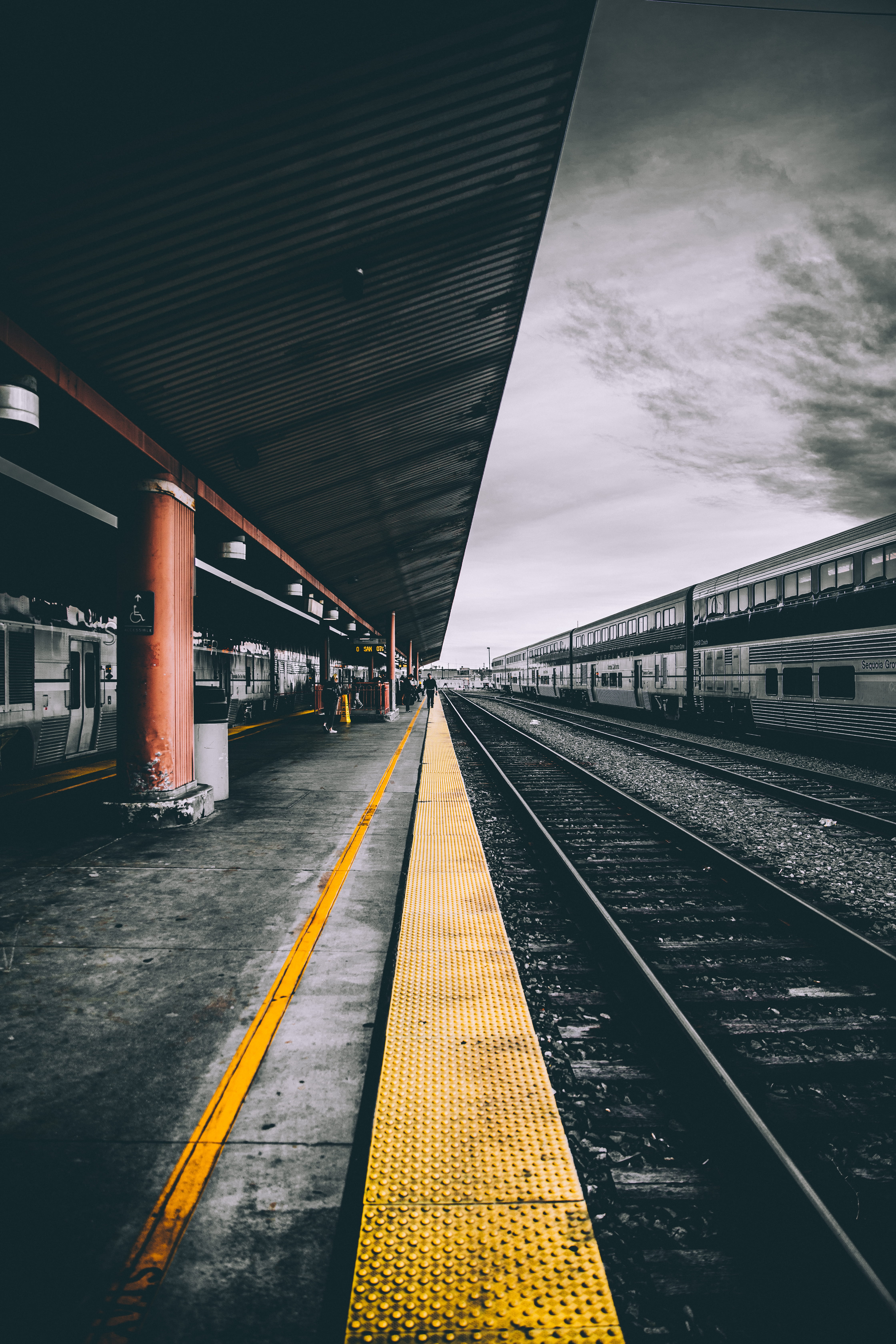 selective color photography of train railways, macro photography of train station under the cloudy sky