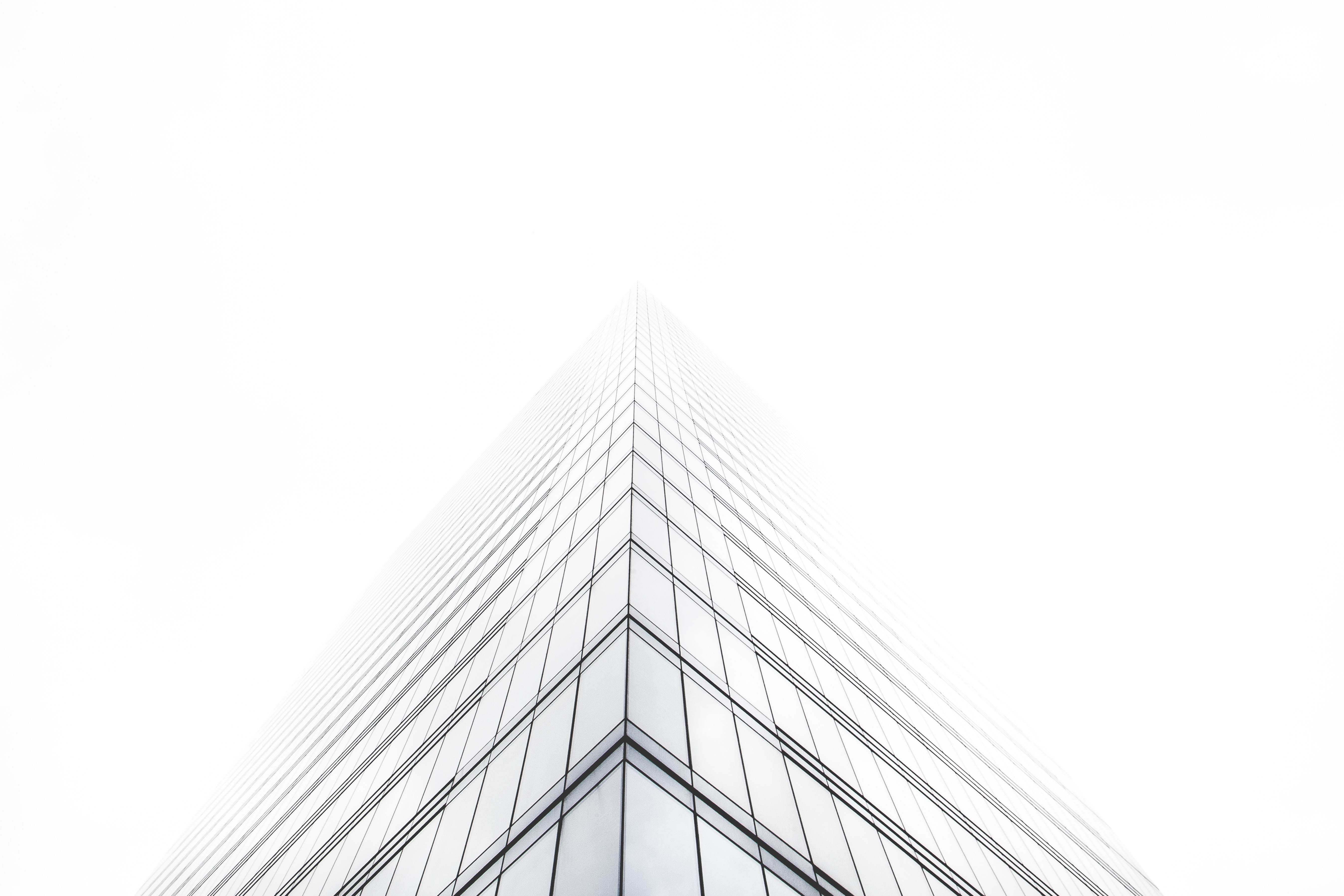 bottom view of glass building, low angle photography of skyscraper under cloudy sky during daytime