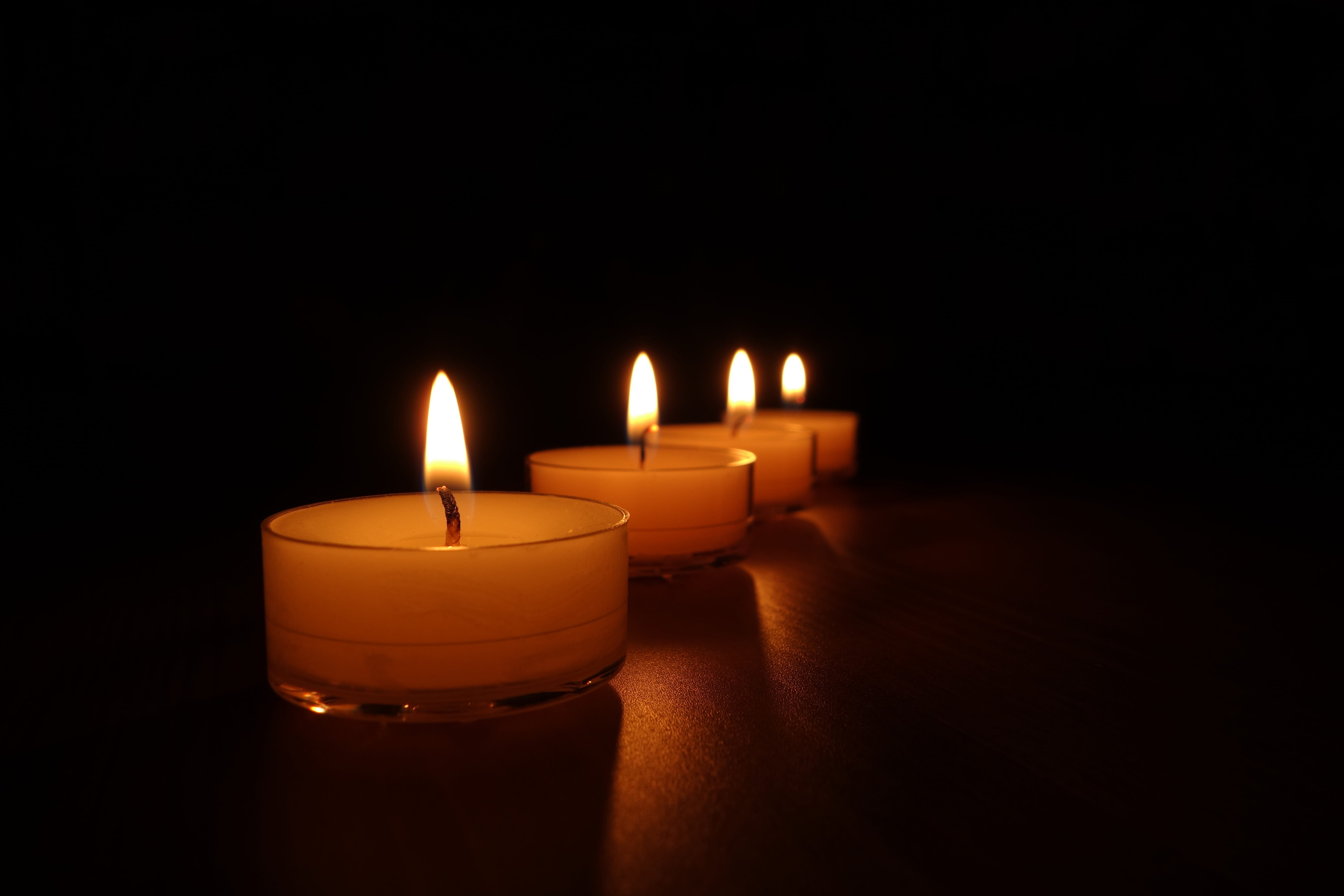 close up photo of four lighted tealight candles, tea lights, candlelight