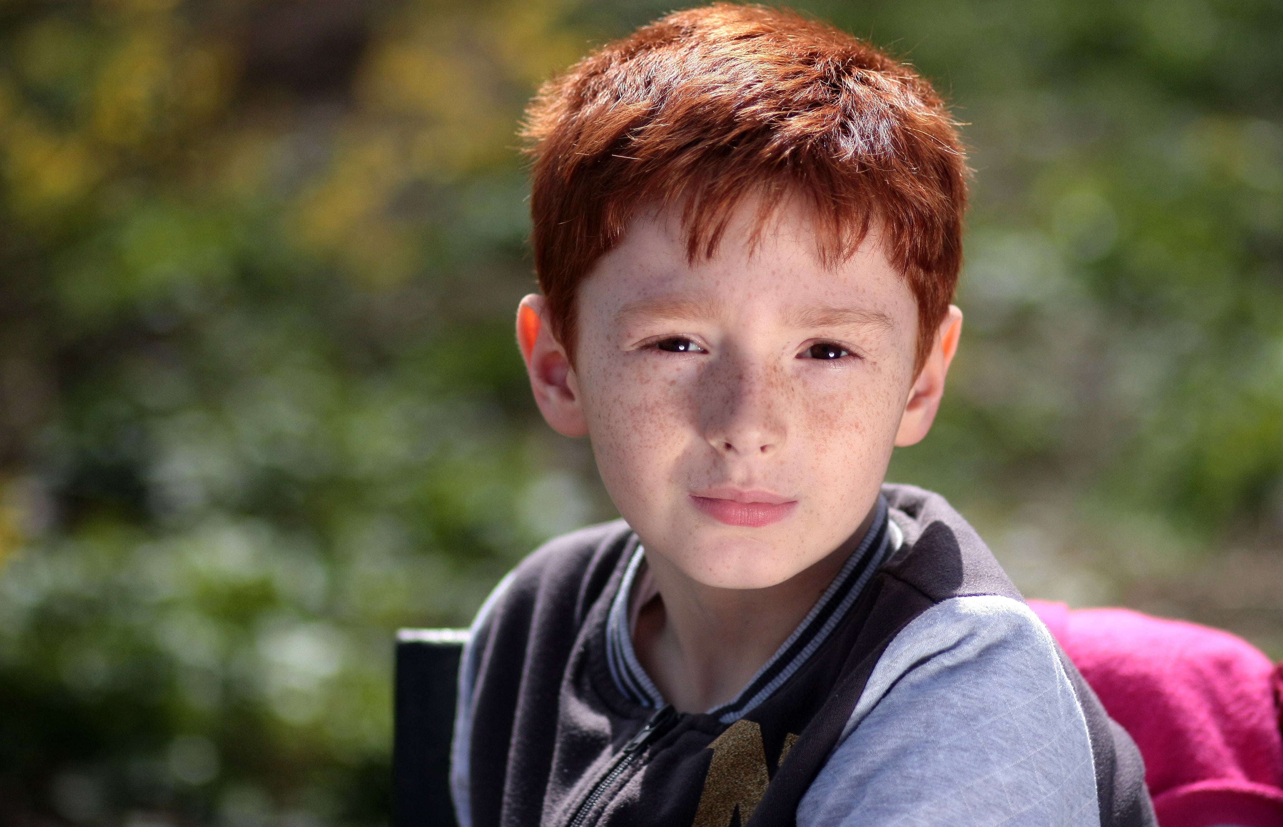 boy wearing gray zip-up jacket, red hair, freckles, portrait