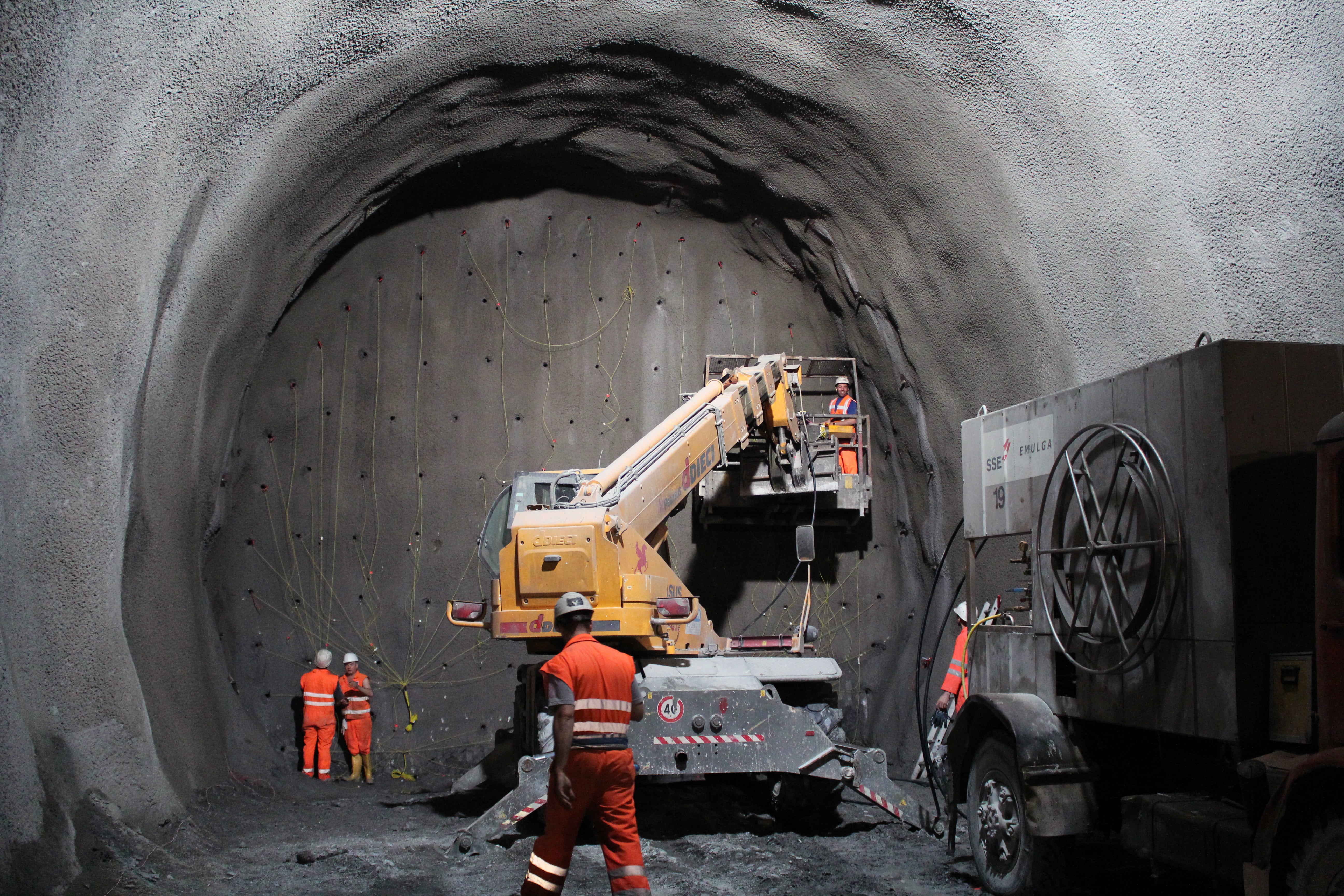 yellow and gray heavy equipment with lift in gray cave, tunnel