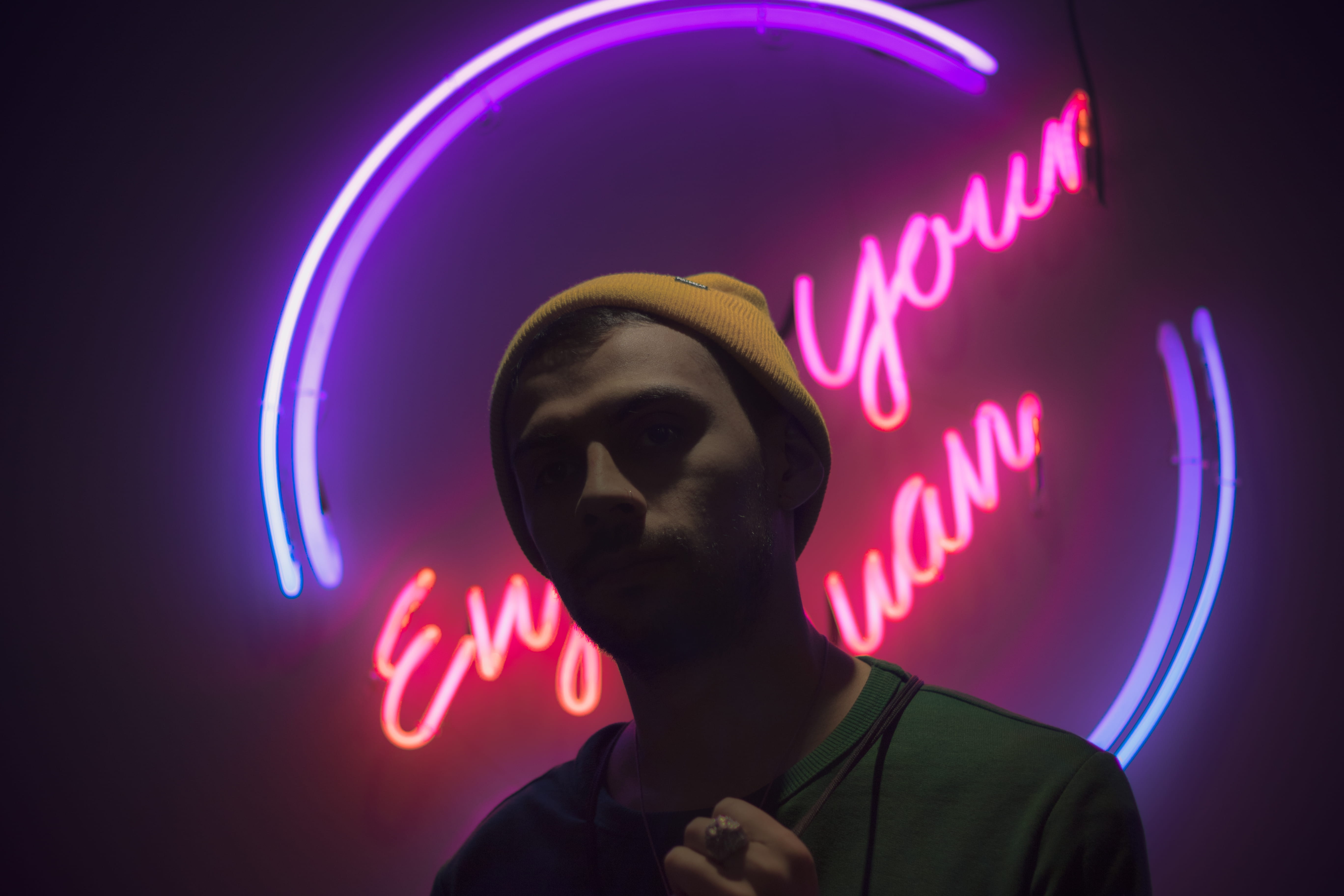 man standing in front of neon light signge, man standing in front of LED signage