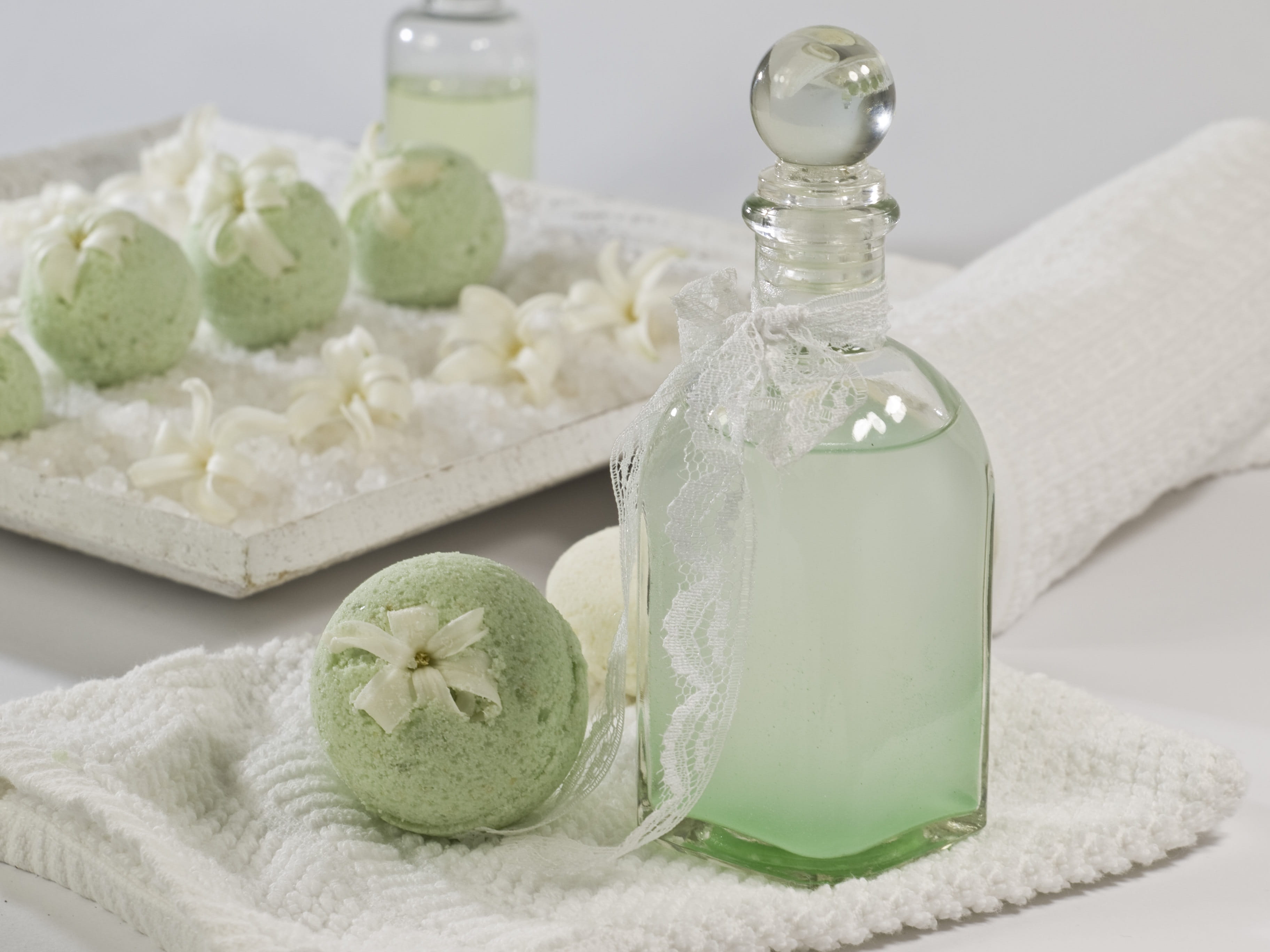 clear glass bottle beside green cake pops placed on white knitted textile